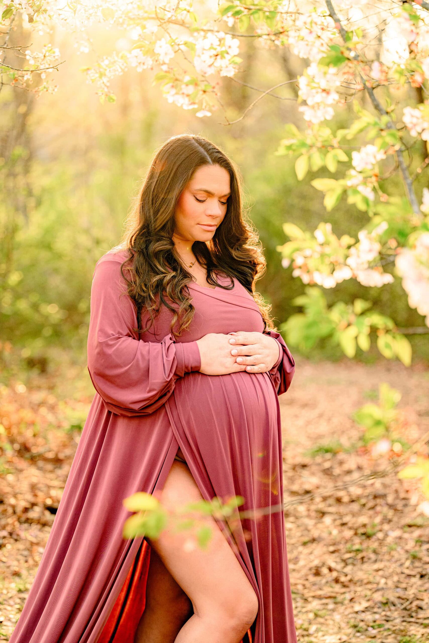 expect mom is glowing in the spring sun with blooms around her while wearing a client closet dress in rose pink in a waxhaw park