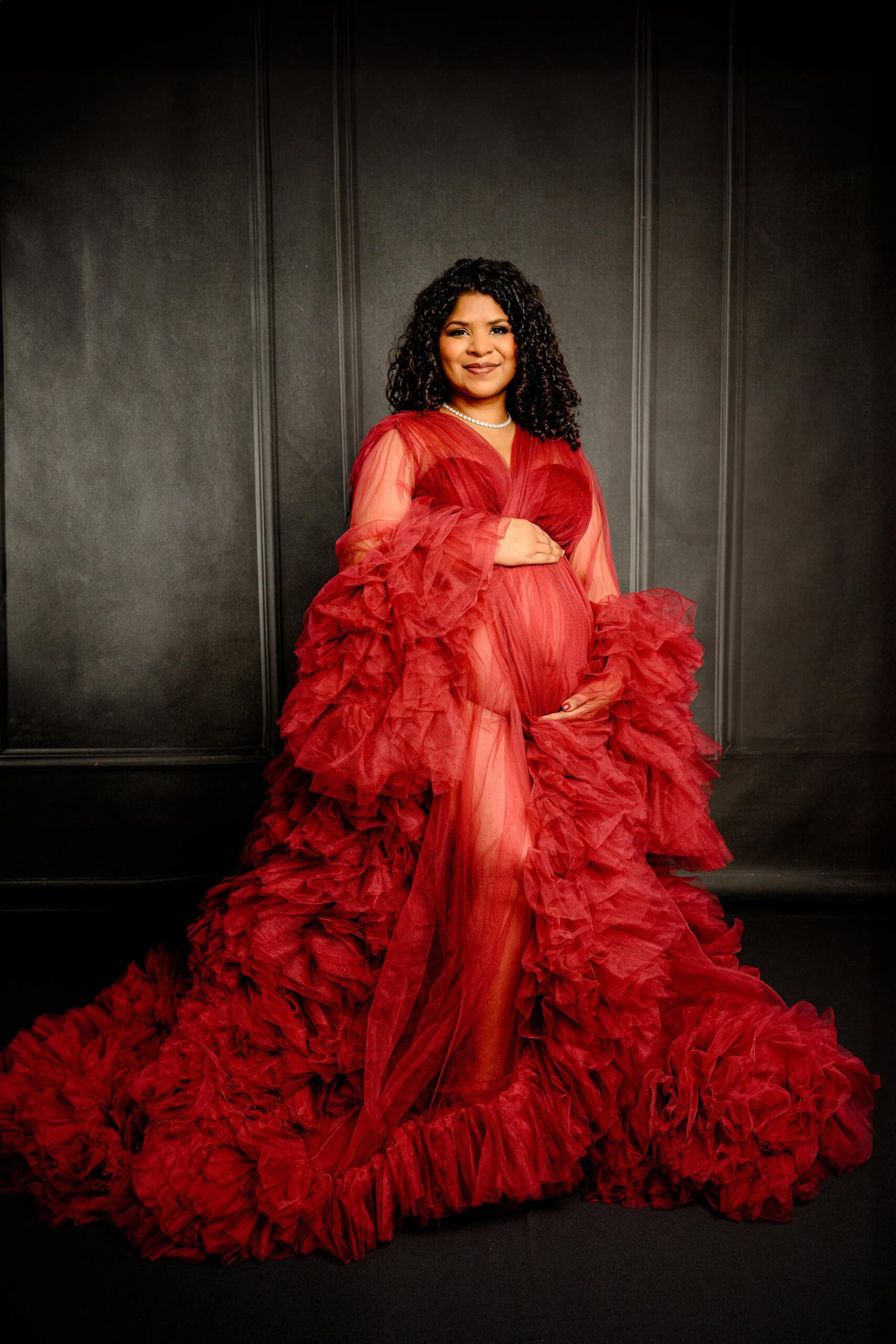 pregnant mother in a red tulle dress poses in a waxhaw studio for her maternity session