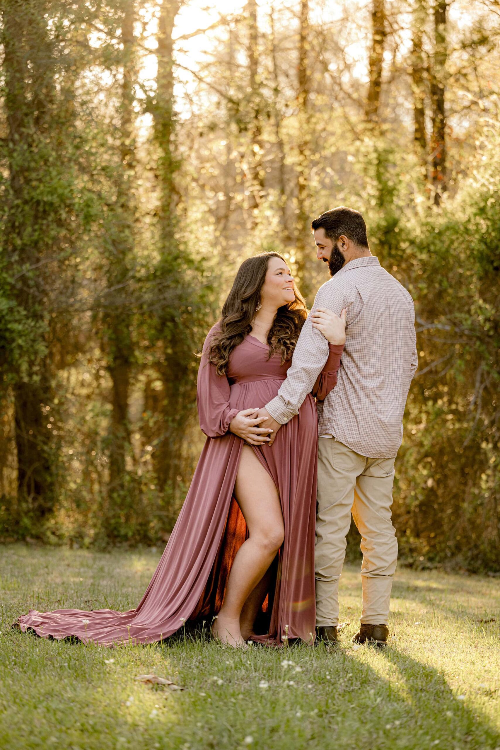 couple maternity photography where mom is wearing a mauve pink dress from my client closet and posing with her arms entwined with dad looking at each other