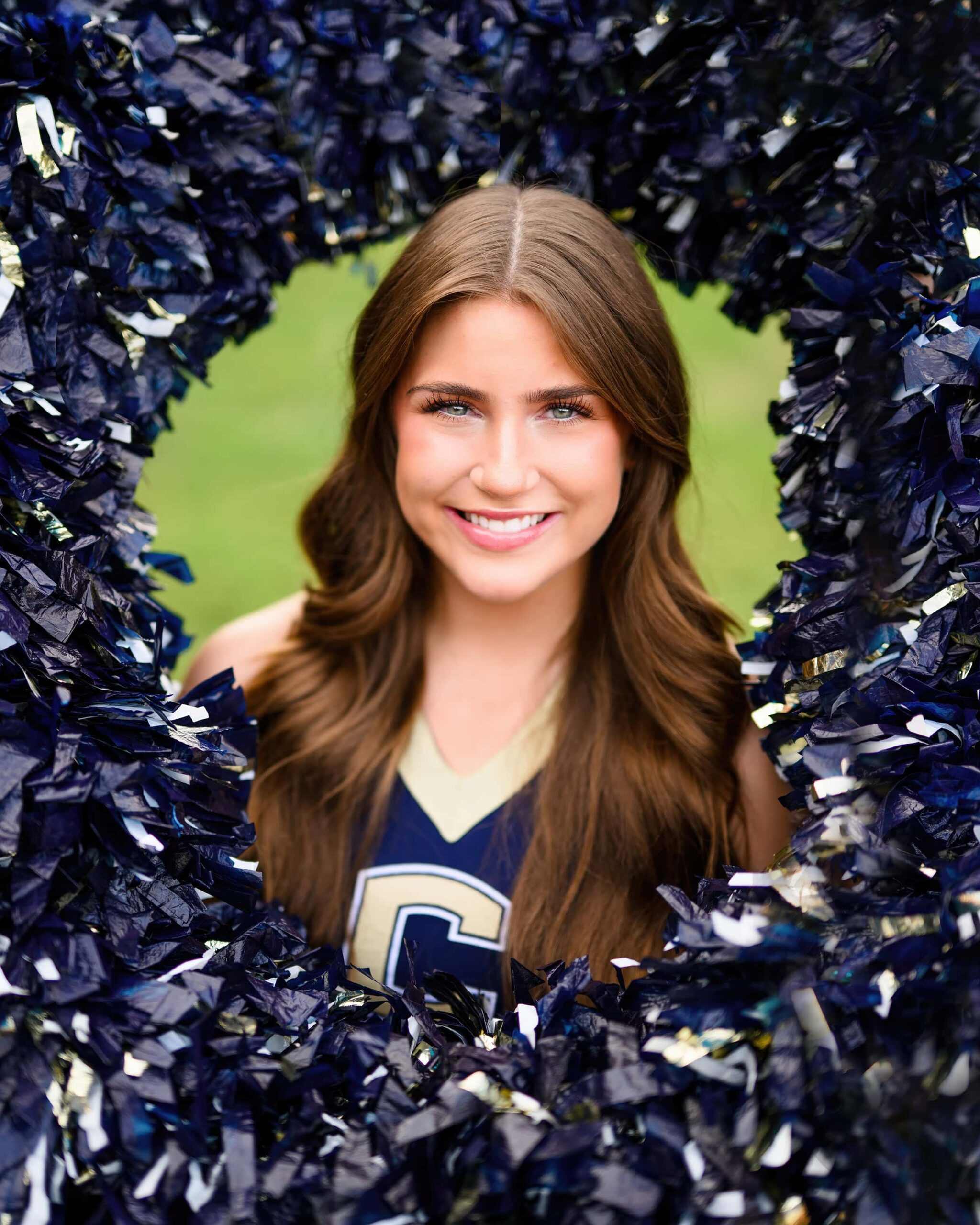 Jayden, a cheerleader from Cuthbertson High School, lies in the middle of a pom-pom ring, surrounded by poms in a circle around her head.