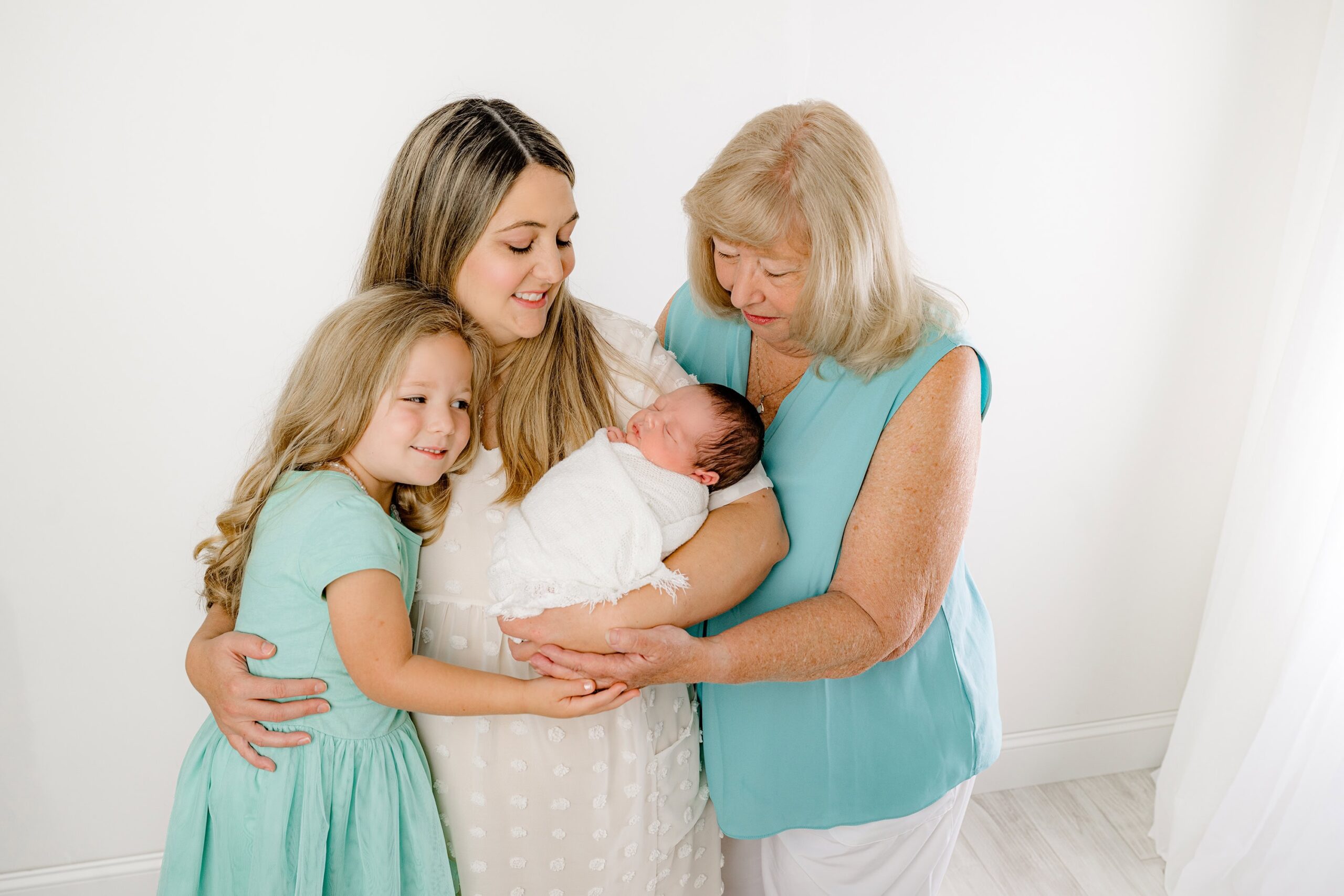 A tender moment as the mom cradles her newborn baby, with her own mother on the left and her daughter on the right, showcasing the deep grandparent love and family connection.