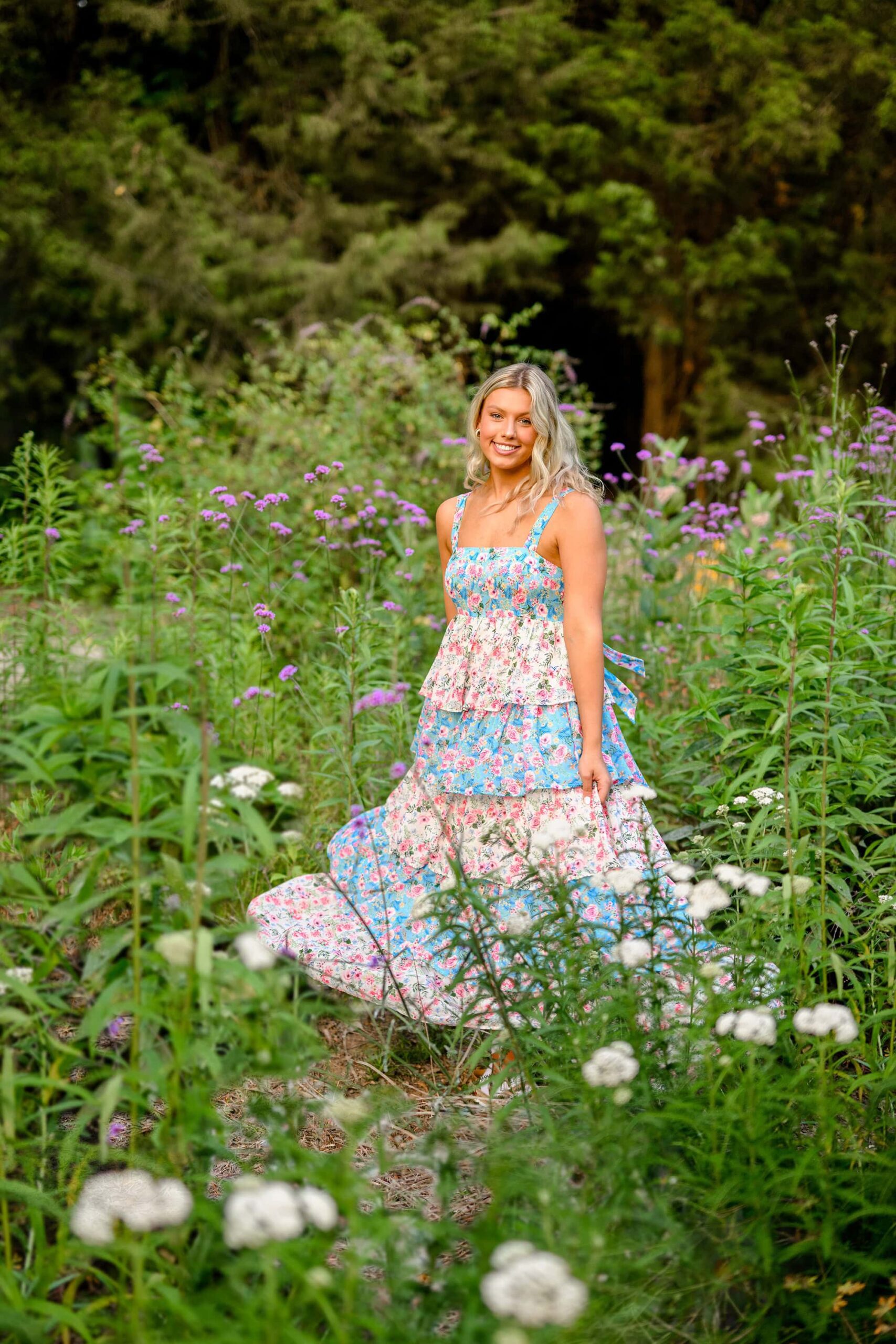 blonde union county graduate twirls her dress in a flower garden wearing a flower dress