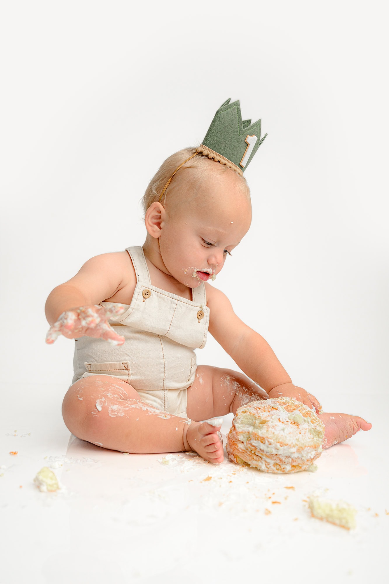 little boy is engrossed in his cake smash for his first birthday