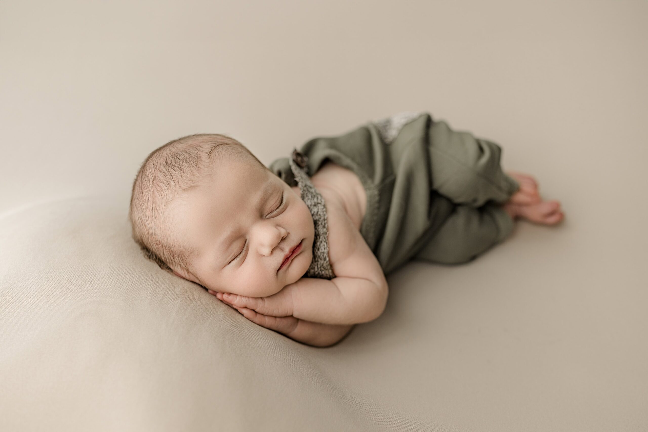 newborn boy posed in green laying on his side