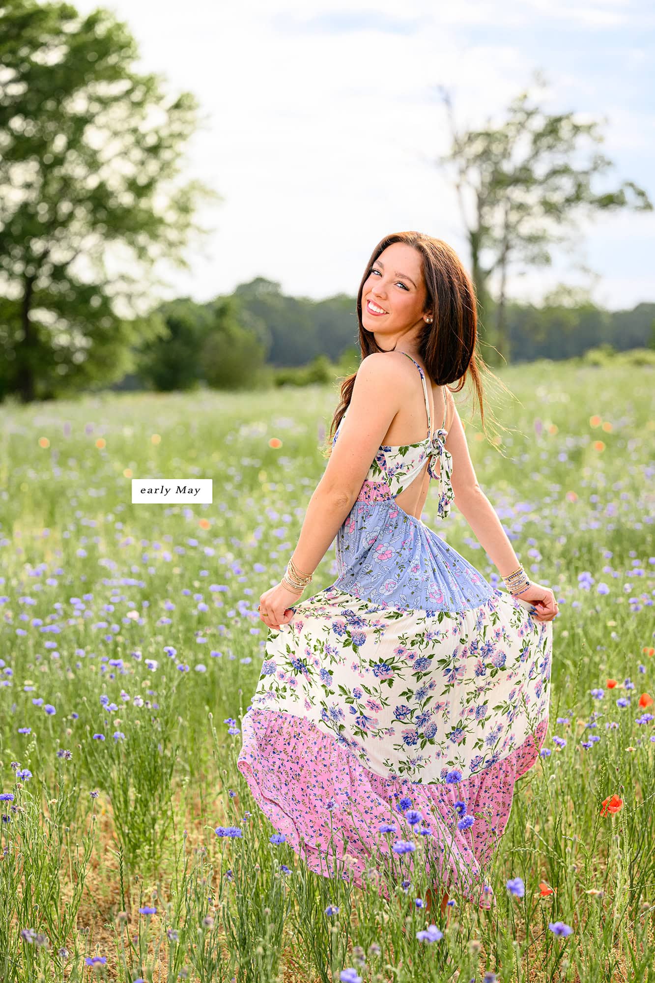 dark hair girl looks over left shoulder while twirling her dress in the late spring floral fields