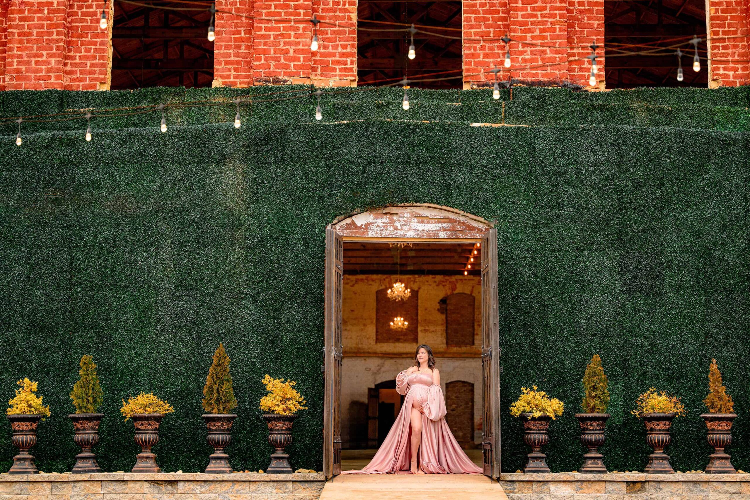 charlotte mother wears a pink satin dress posed in the arch doorway of the providence cotton mill.