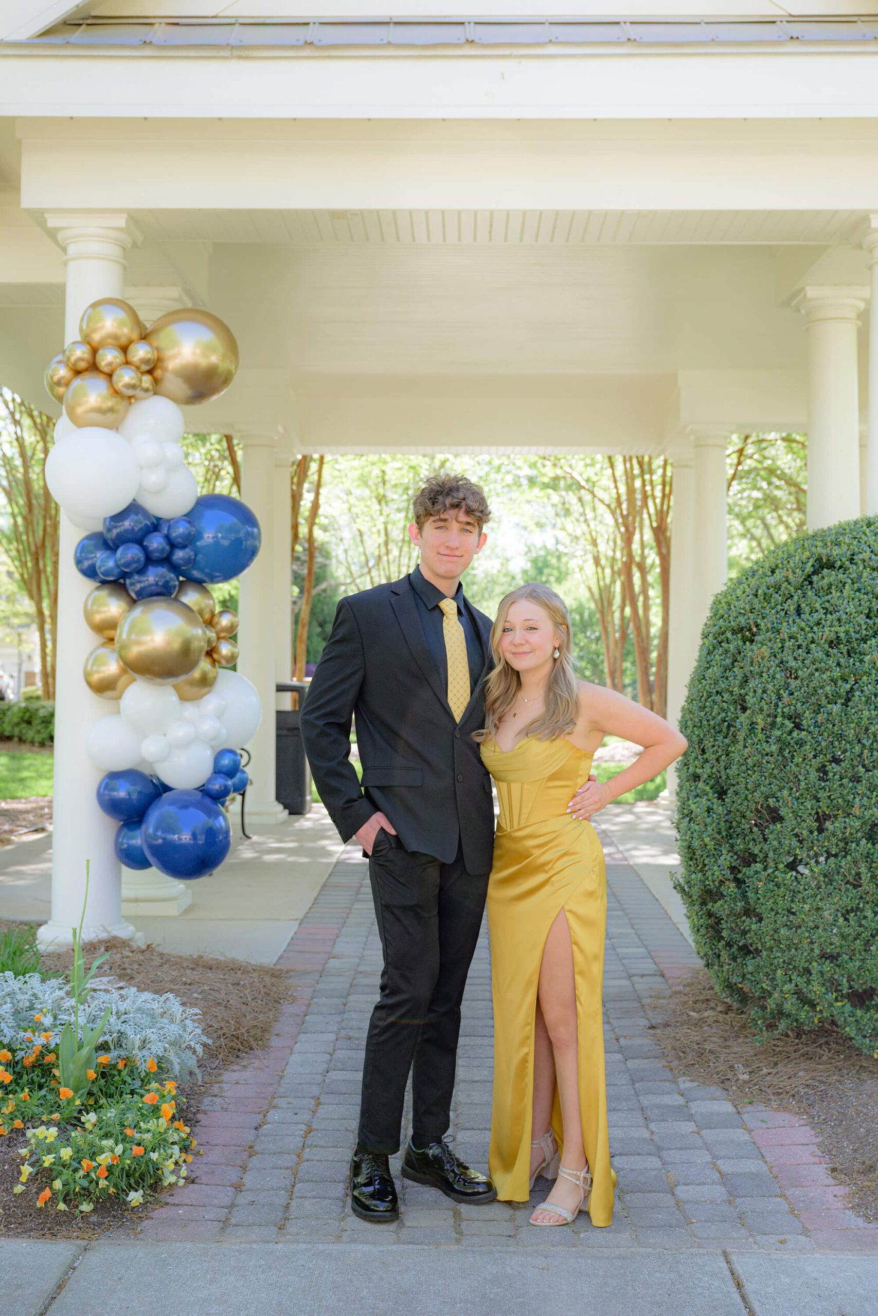guy in black suit and yellow tie standing beside his prom date in a yellow dress