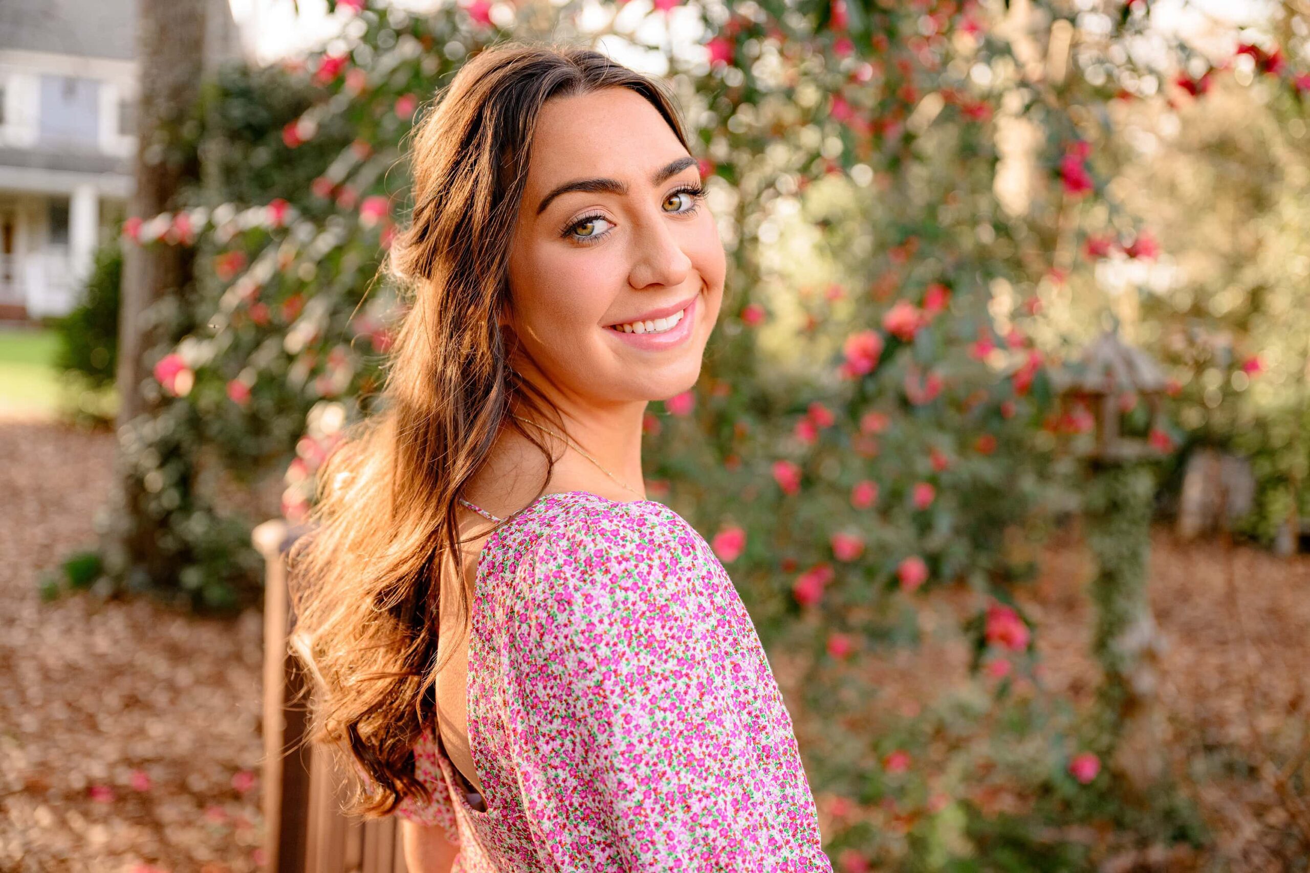 union county grad poses amongst the blooms during her senior photos with the shining on her brown curls
