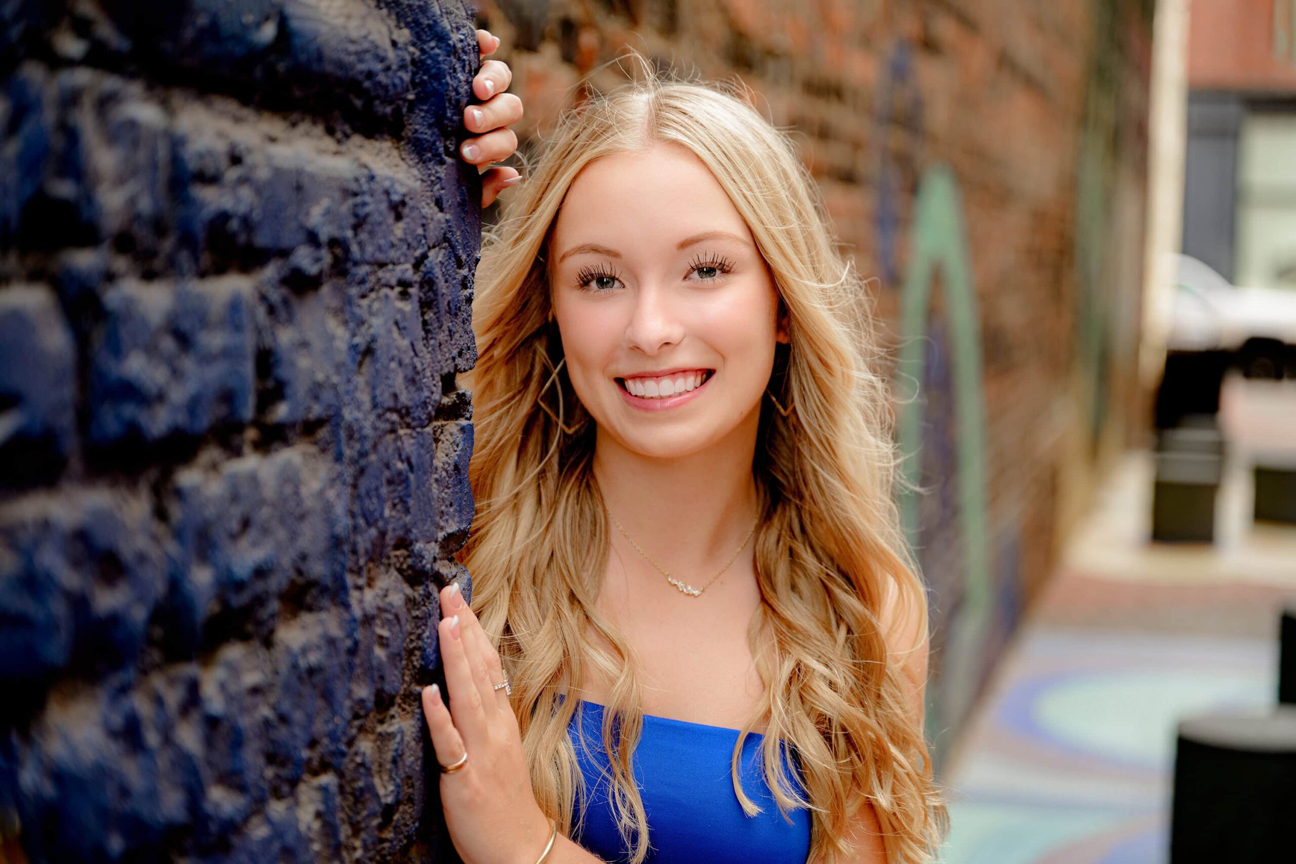 Cuthbertson grad with blonde hair leans against a brick wall in downtown rock hill, sc