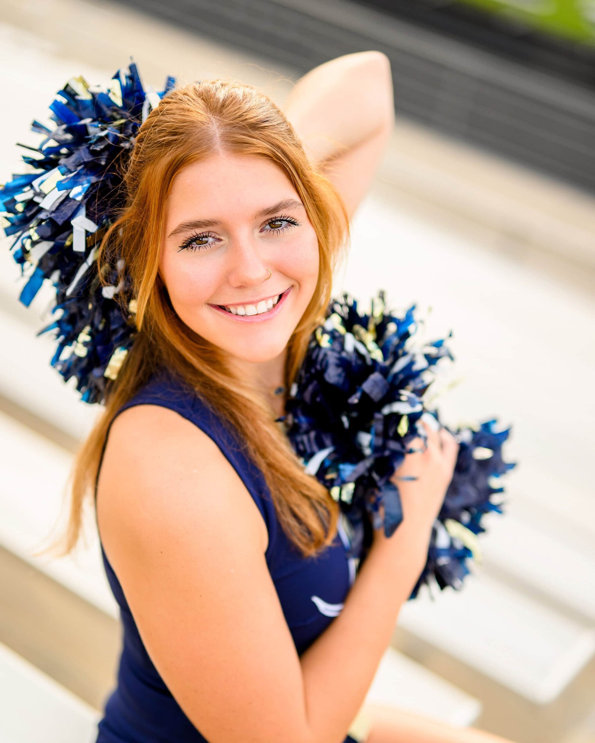 redheaded waxhaw senior poses with her poms by her face wearing her cheer uniform