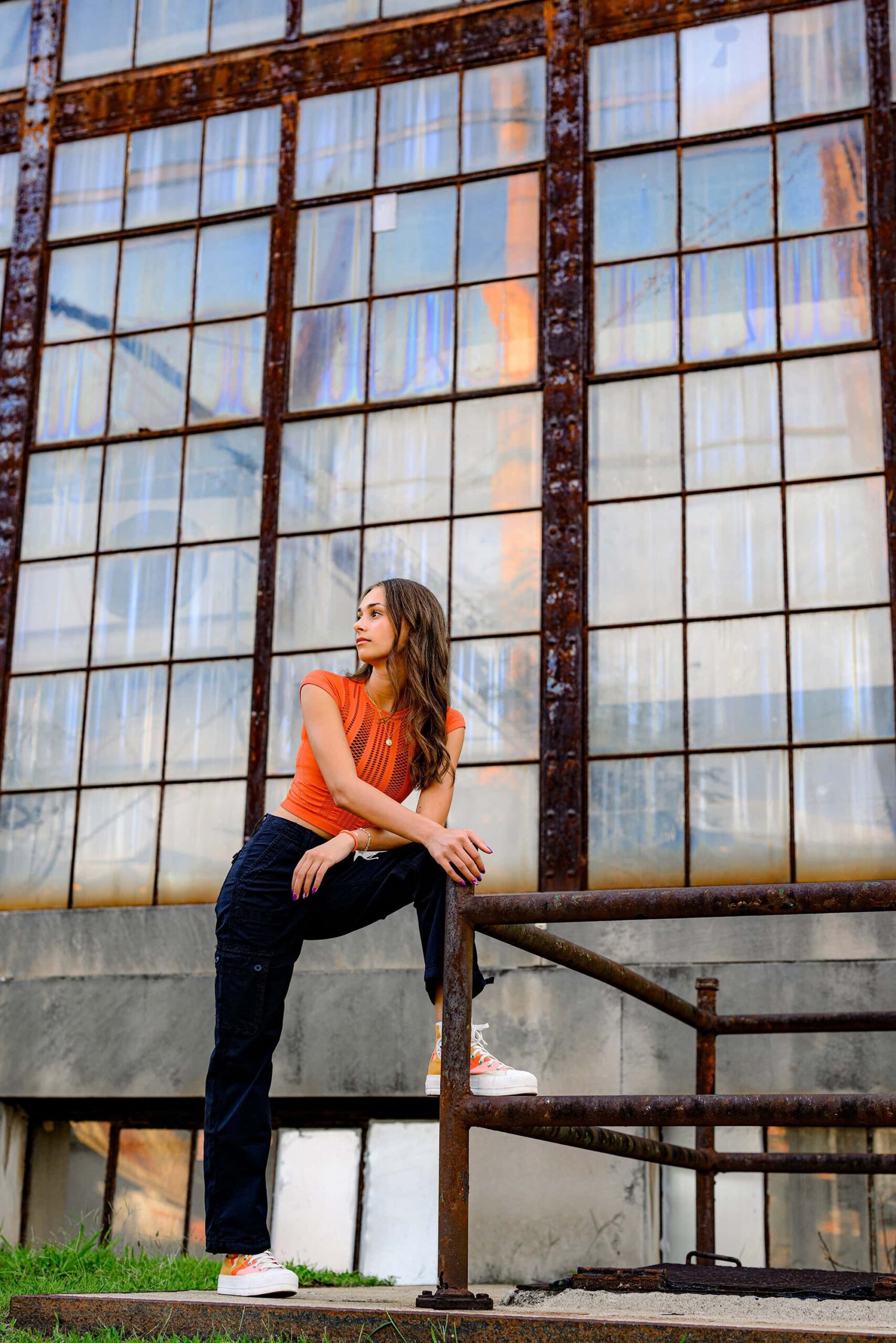 industrial vibes for this charlotte senior during her photo session in camp north end. she is wearing black pants and an orange top