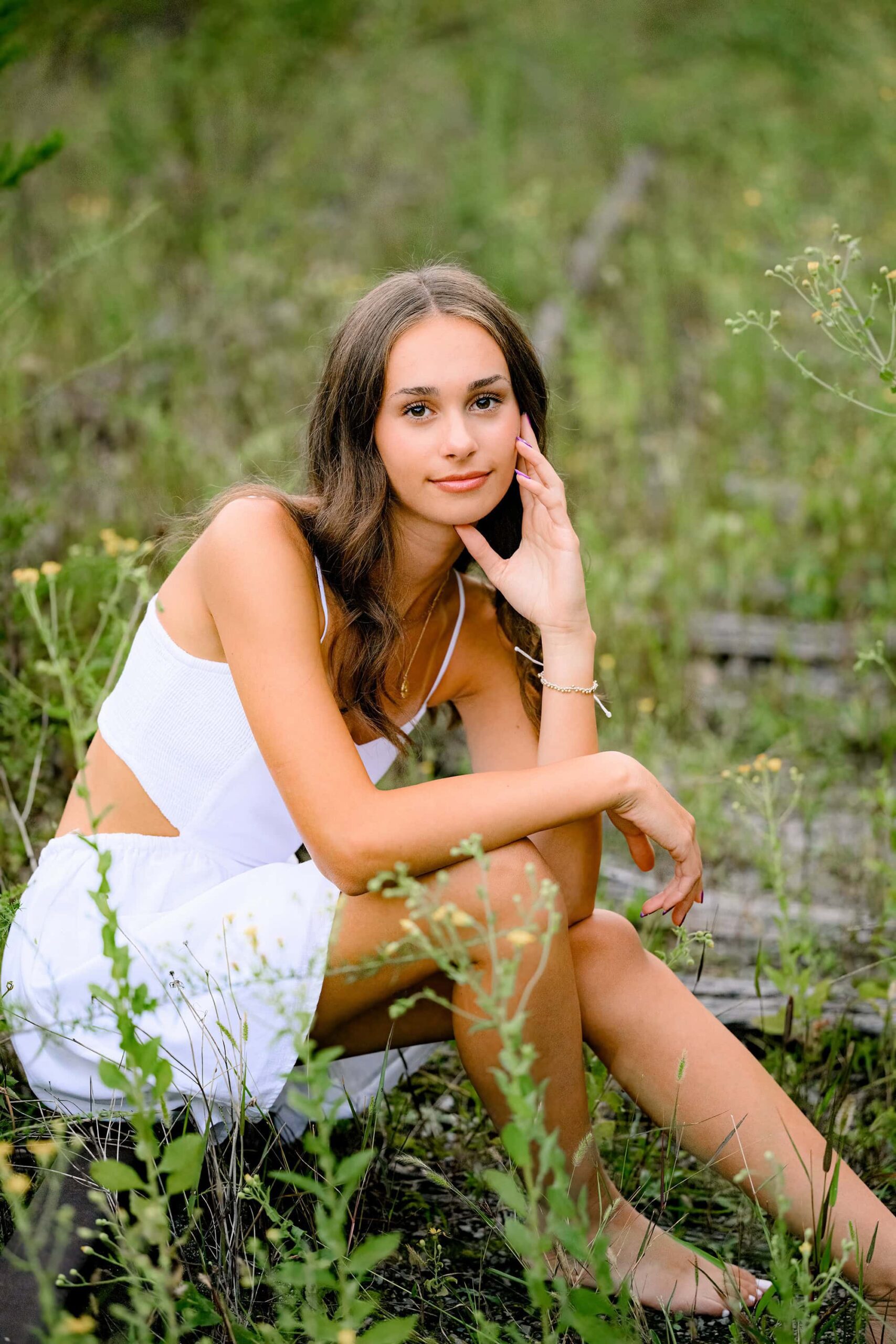 charlotte senior sits on old train tracks at this unique senior photo session location wearing a white dress