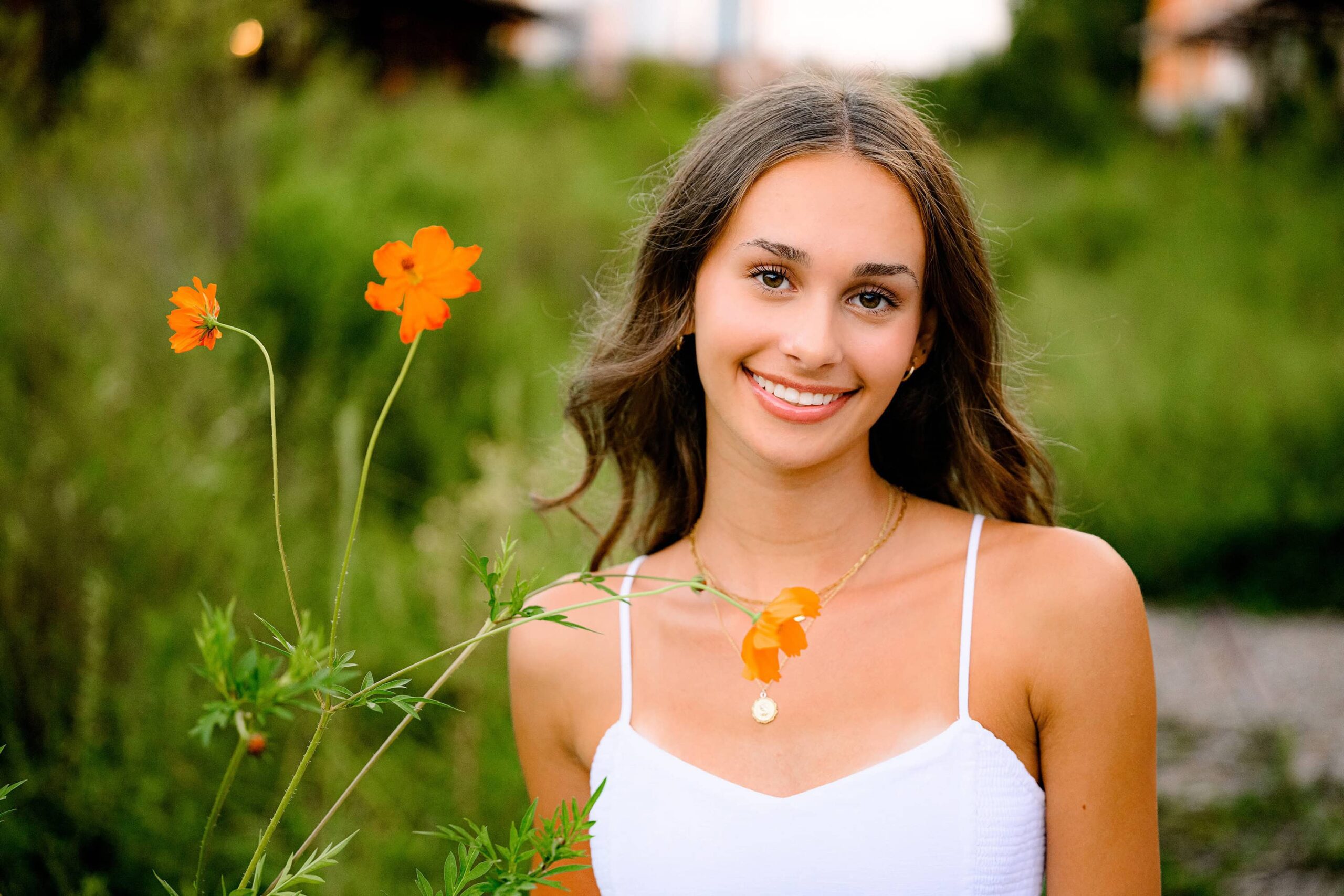 close up photo of ardrey kell senior at this unique senior session location in uptown charlotte with orange flowers beside her while wearing a white dress