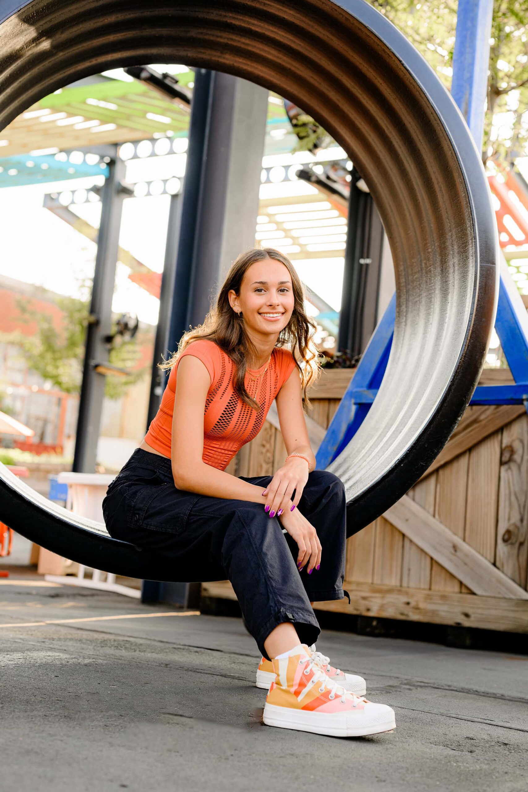 senior from ardrey kell high school sits in a large hoop in camp north end wearing black pants and an orange top