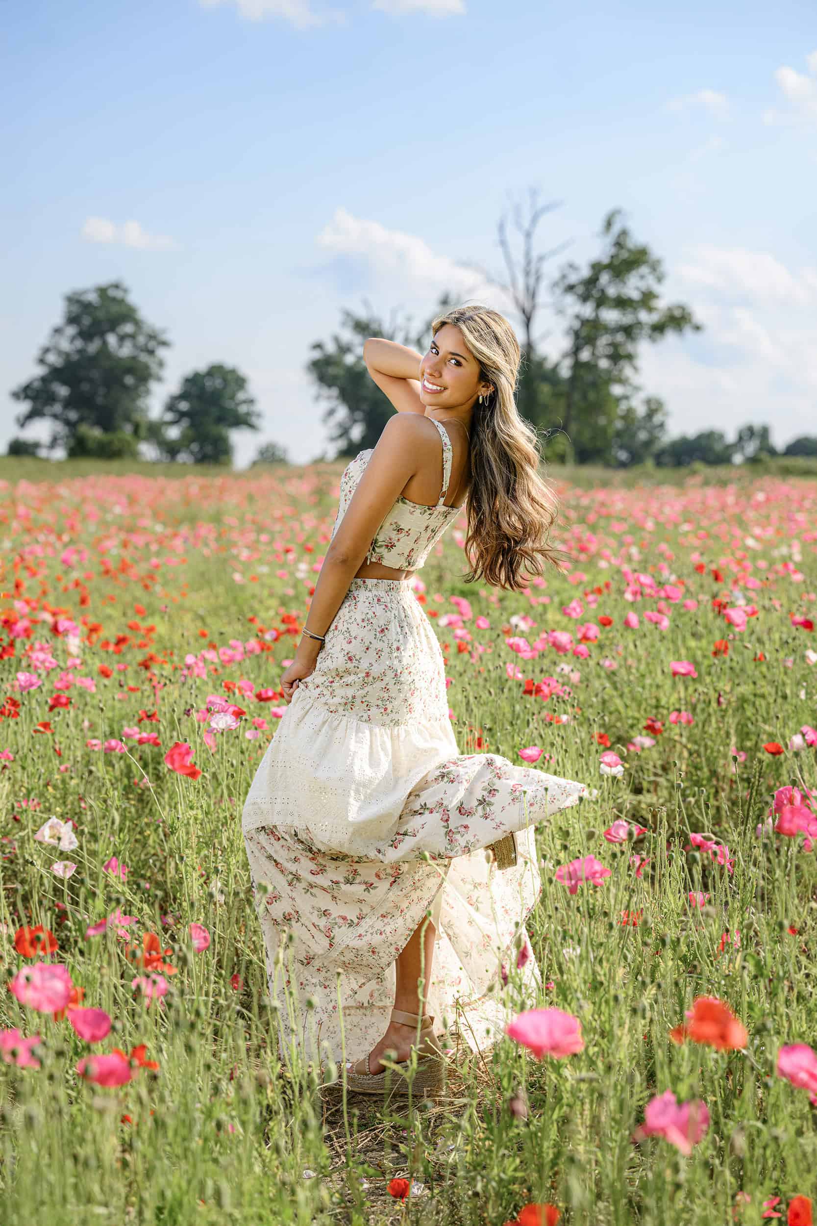 CHS Senior in a floral dress kicks up a shoe during her graduate session in a Charlotte Flower Field with a Grad Photographer