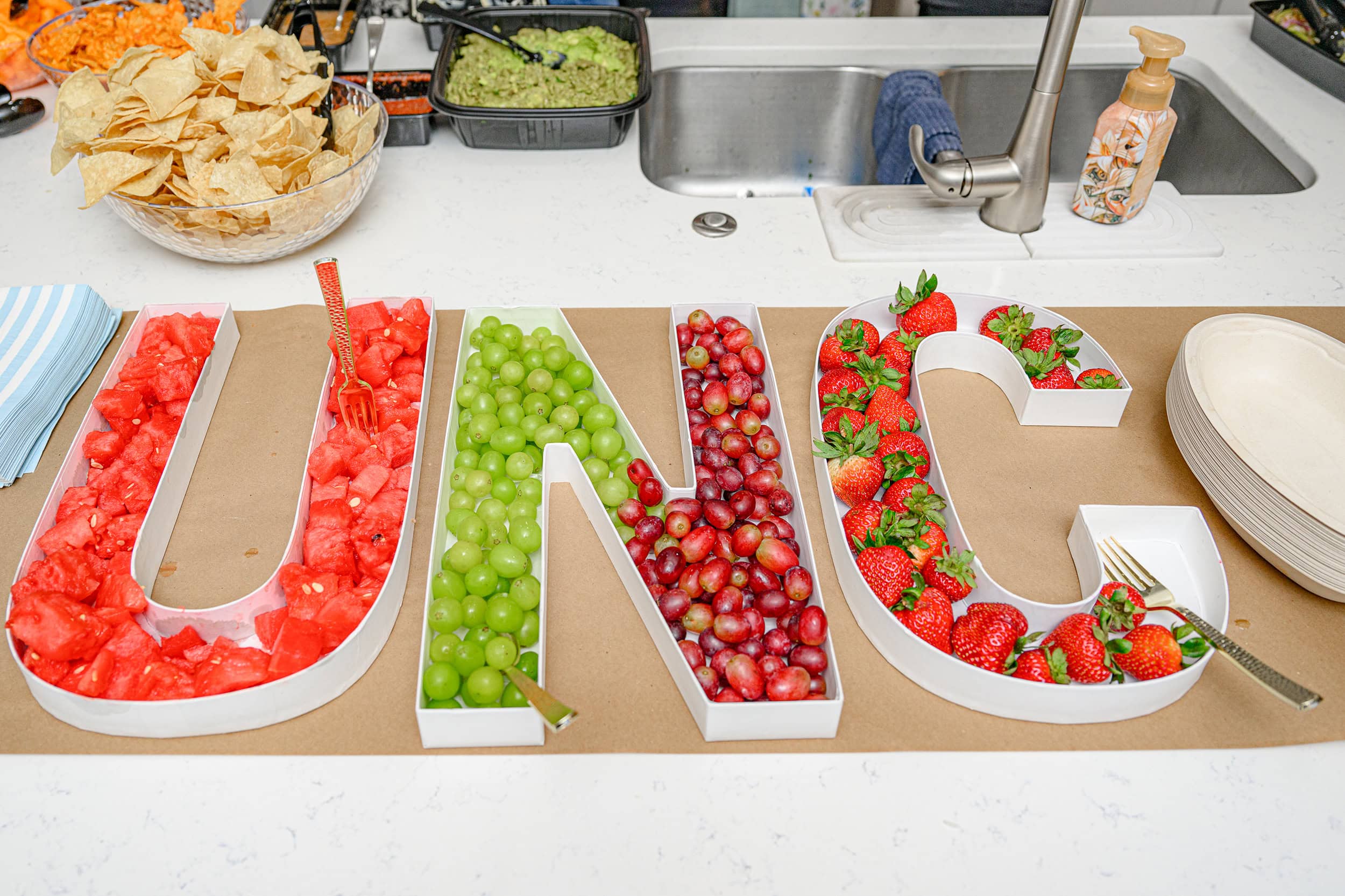 fruit bar set up in letters UNC filled with watermelon grapes and strawberries