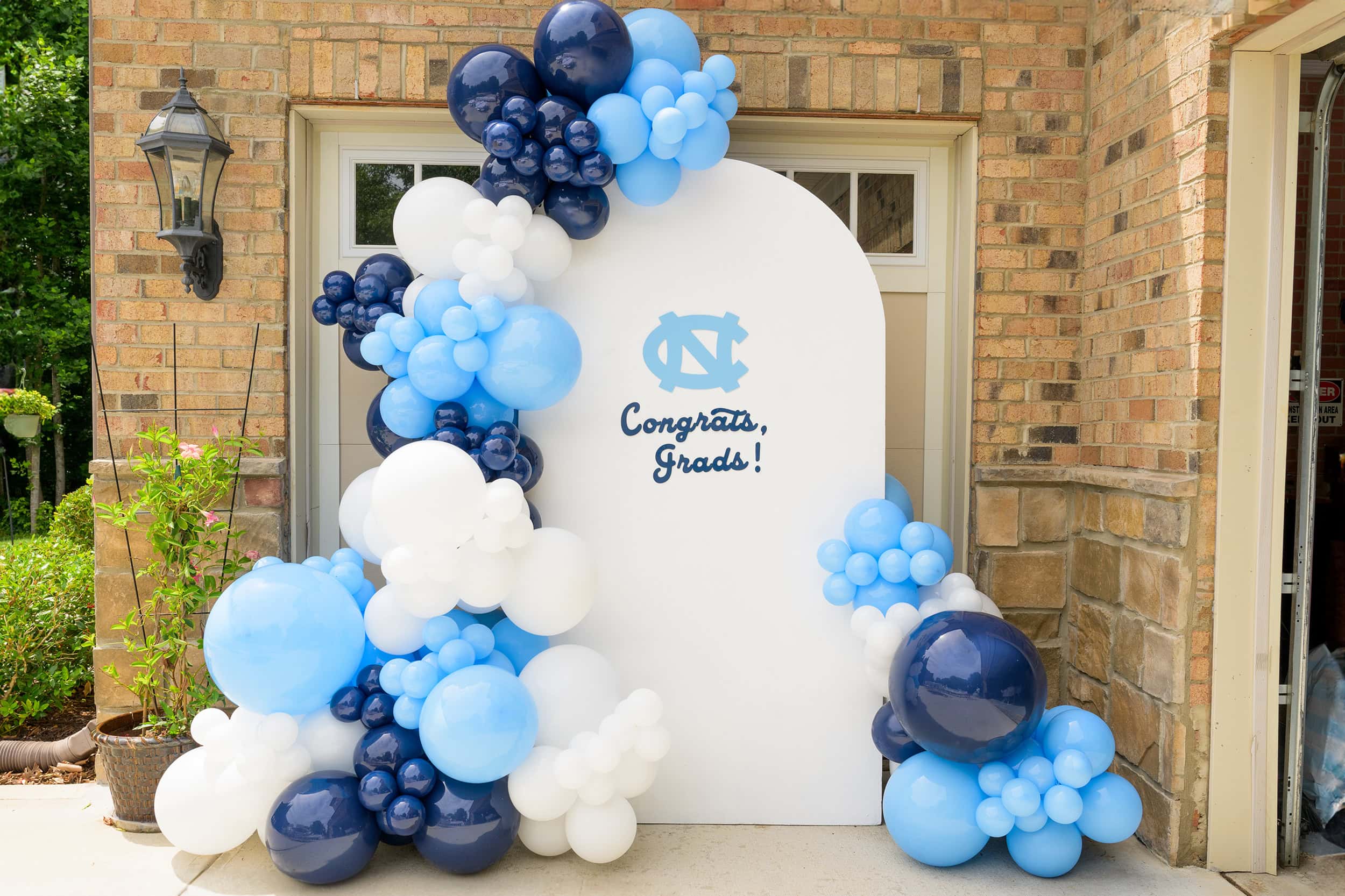 senior party photo in the backyard of a family home of a UNC CHapel hill themed balloon arch