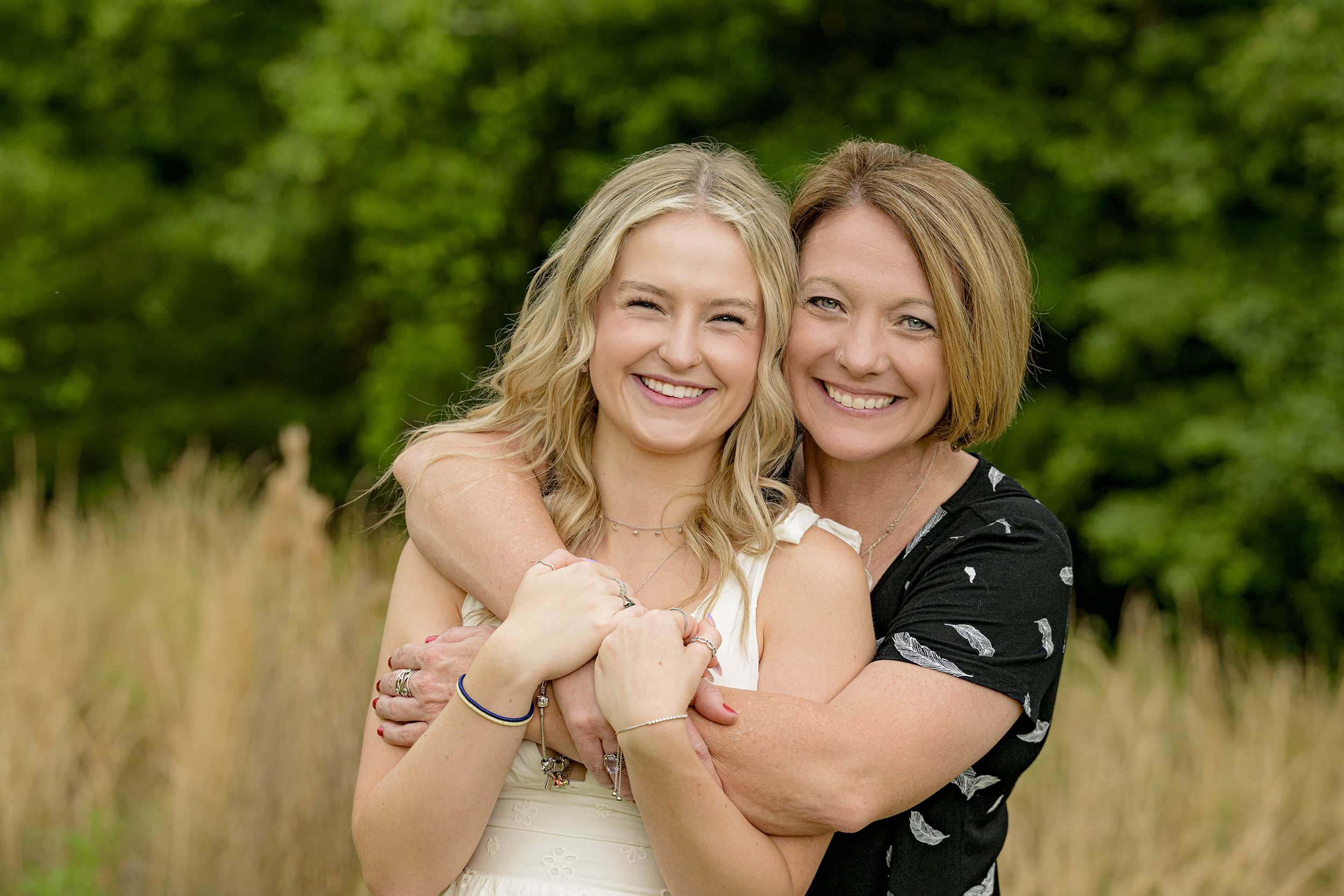 charlotte mother and daughter photo with mom wearing black and cream and senior wearing white as they hug during her senior portraits