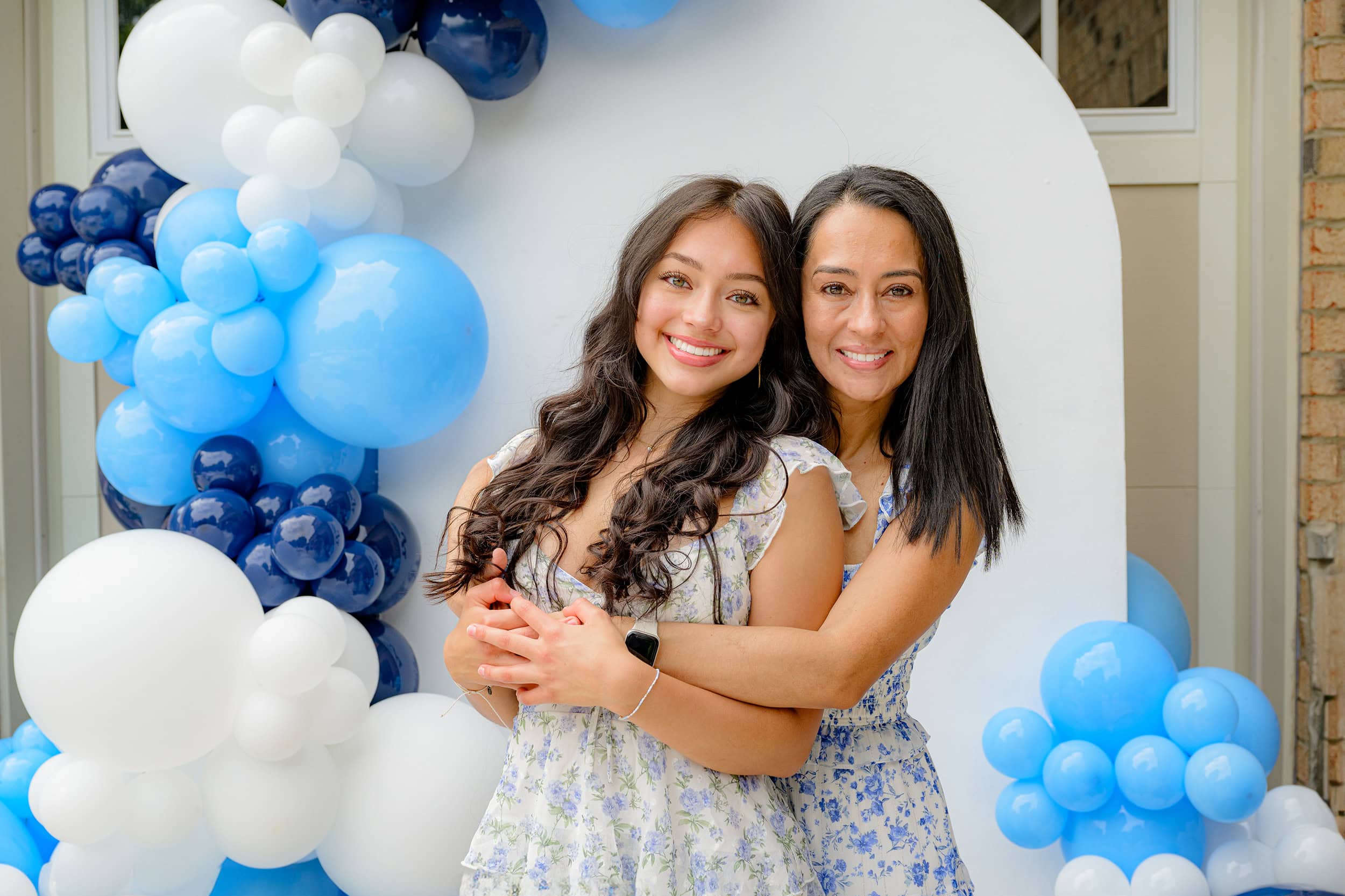 Charlotte High School Graduate is embraced by her mom during her charlotte senior party in front of her UNC CHapel Hill Balloon arch