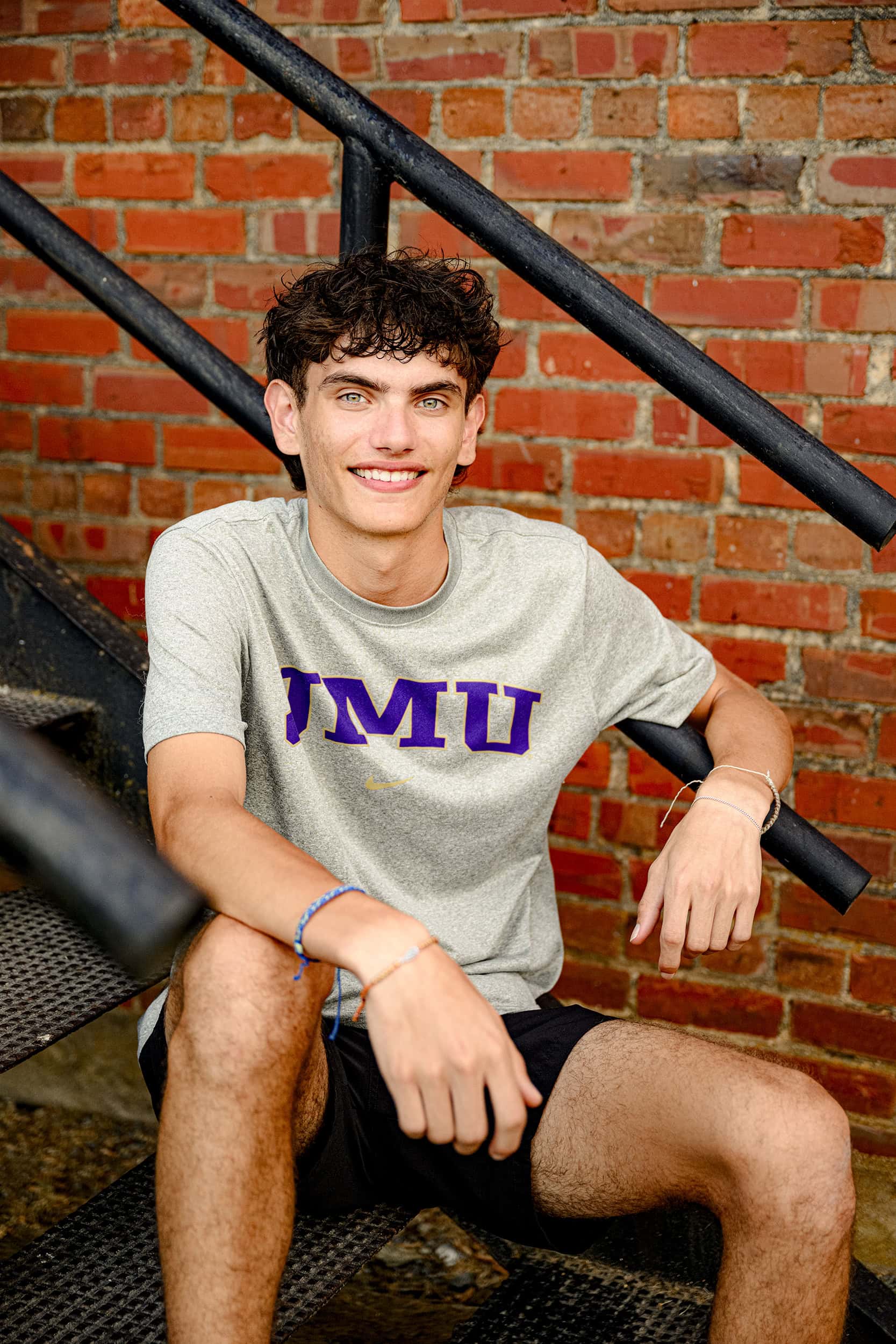 Senior boy from Cuthbertson High School sits on stairs wearing his future college JMU teeshirt