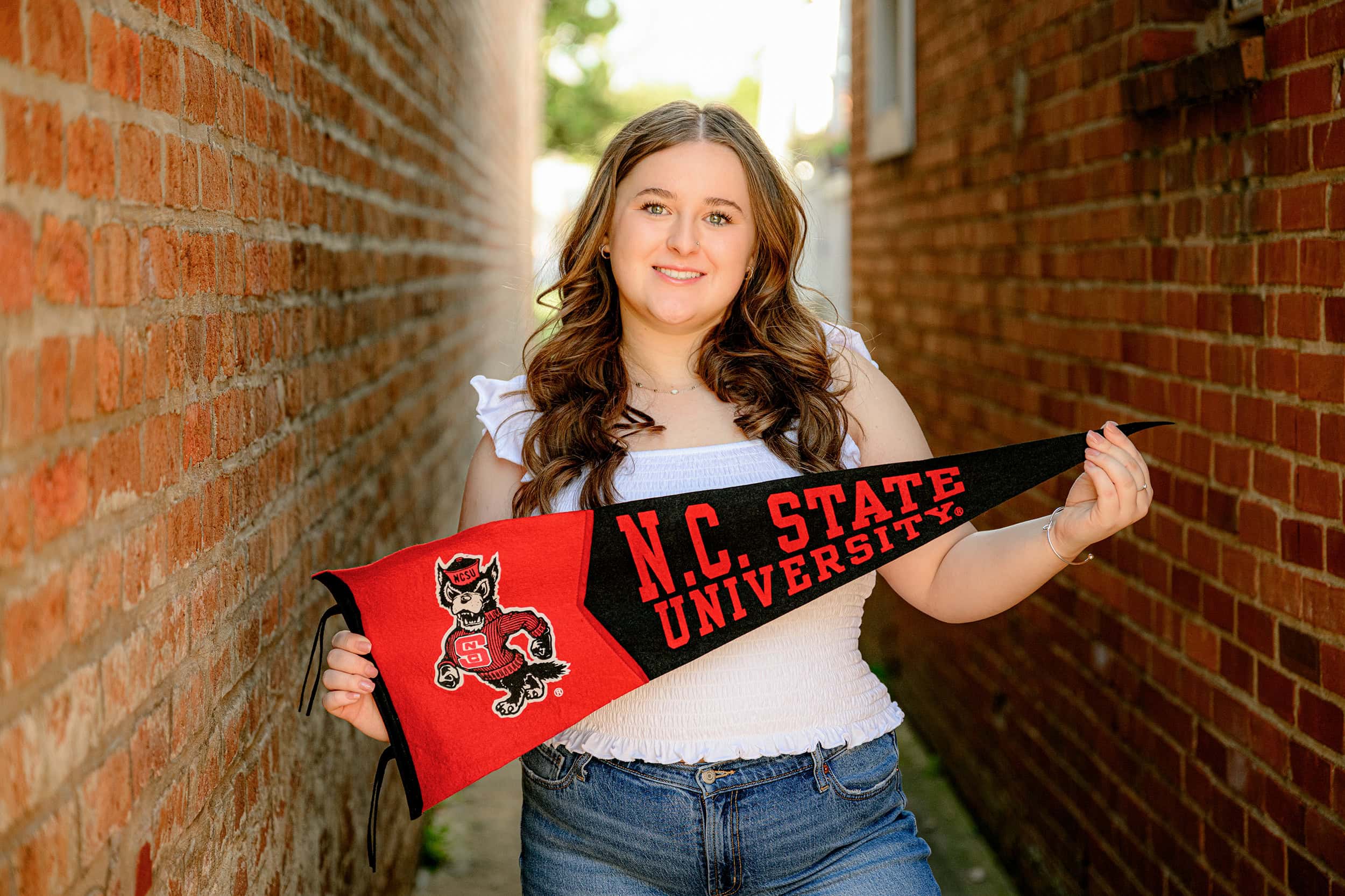 Cuthbertson High School Senior wearing white shirt and jeans holding her future NC State College Pennant for Her Graduation photo for her senior party
