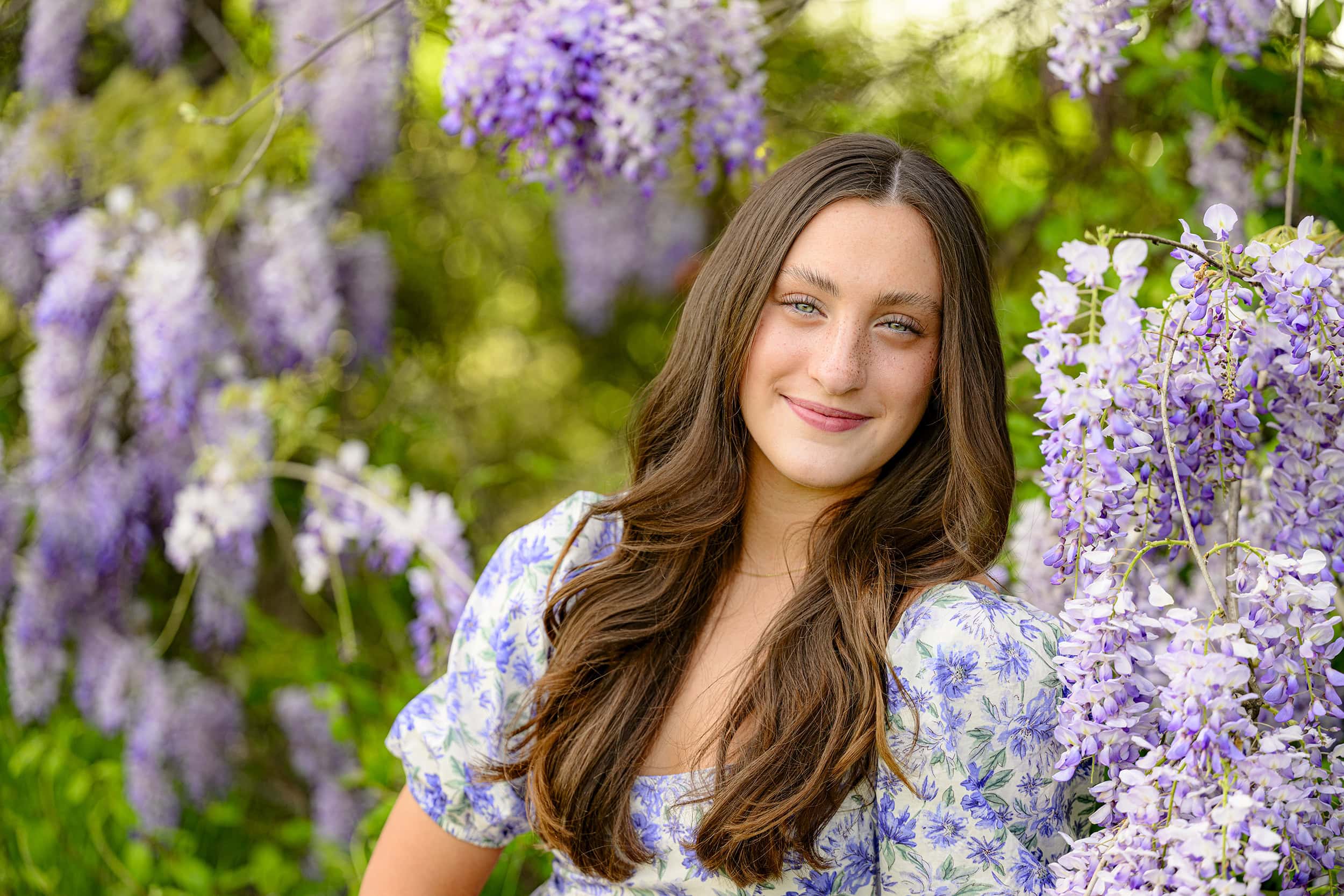 rising senior from charlotte catholic high school's planned senior portrait session surrounded by early spring wisteria blooms while wearing floral dress