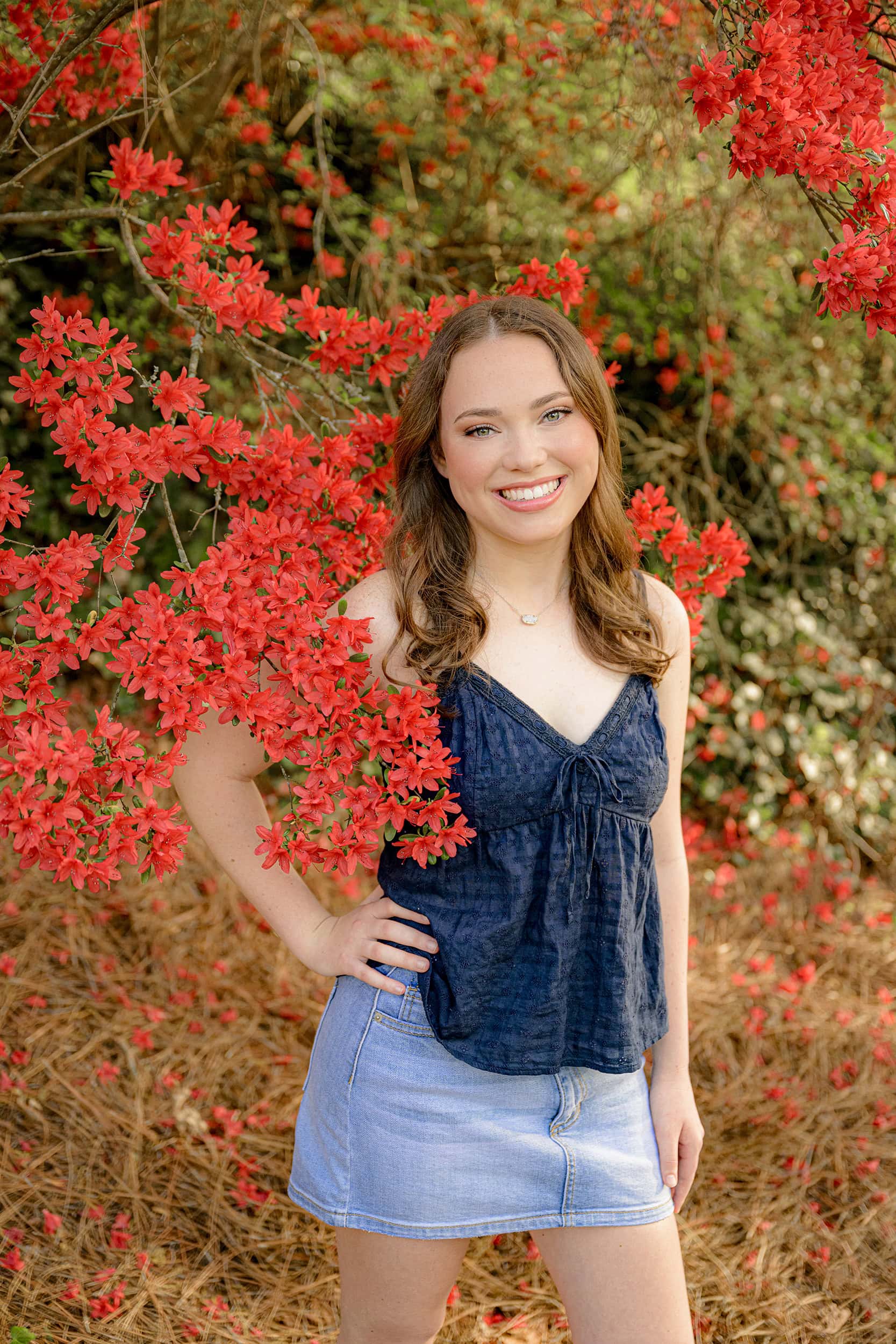 red blooms surround this auburn hair cuthbertson senior wearing a navy tank top and jean skirt