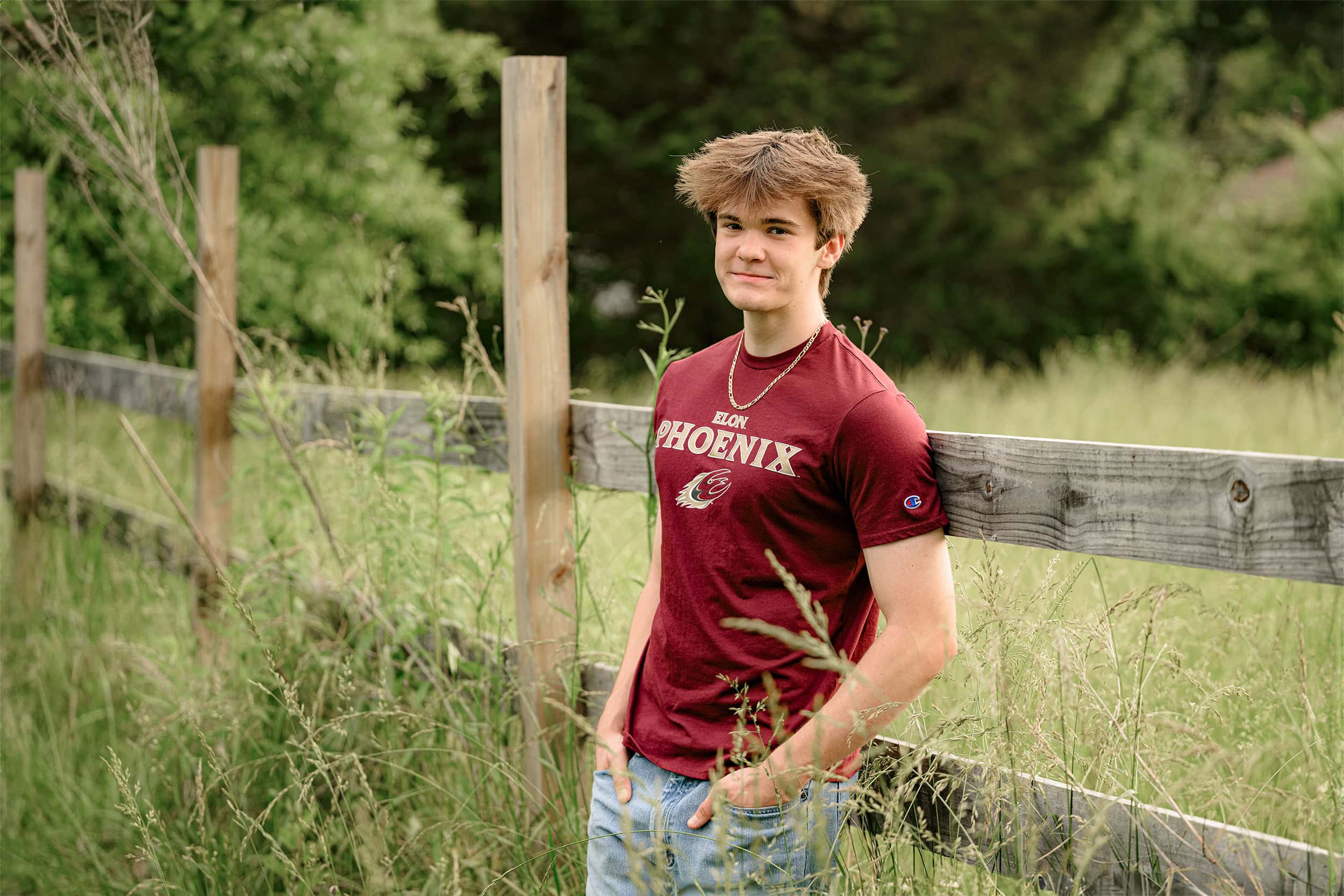 charlotte senior boy stands in maroon t-shirt in field