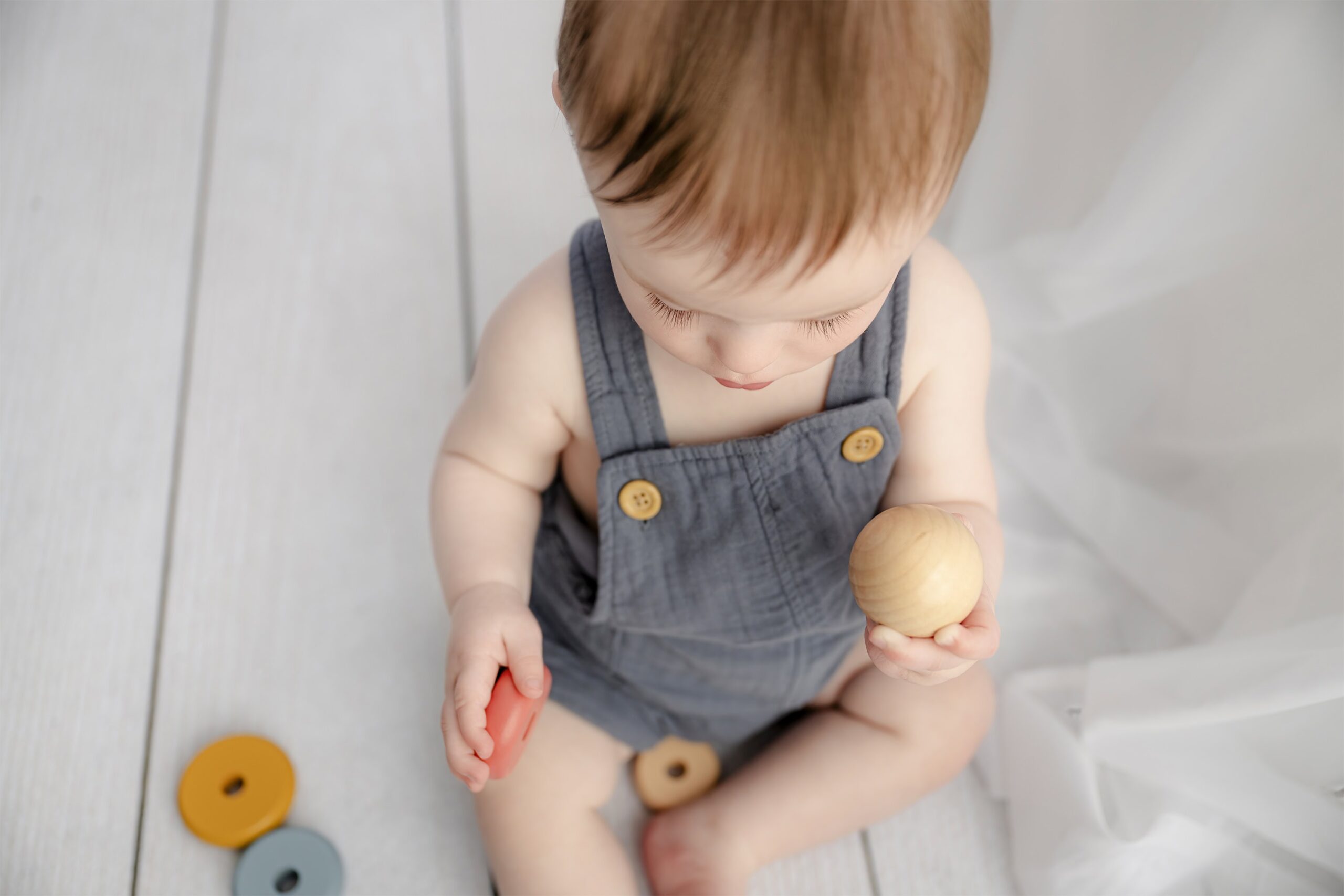 baby toys that are baby safe and a little overhead image of a 8 month old dressed in linen overalls