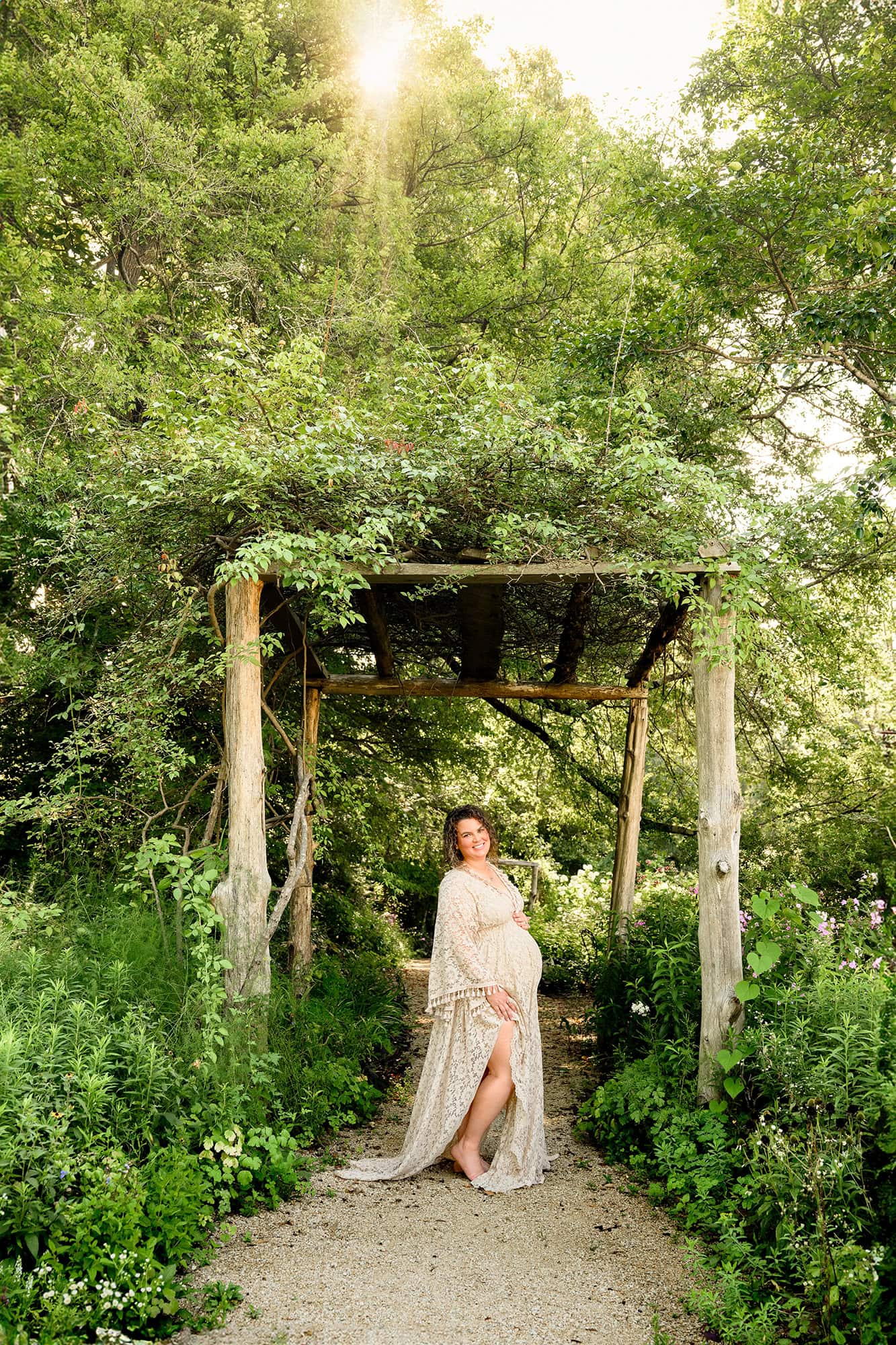 Expectant Charlotte mother dressed in boho style maternity dress posed under a natural arbor in a south carolina venue