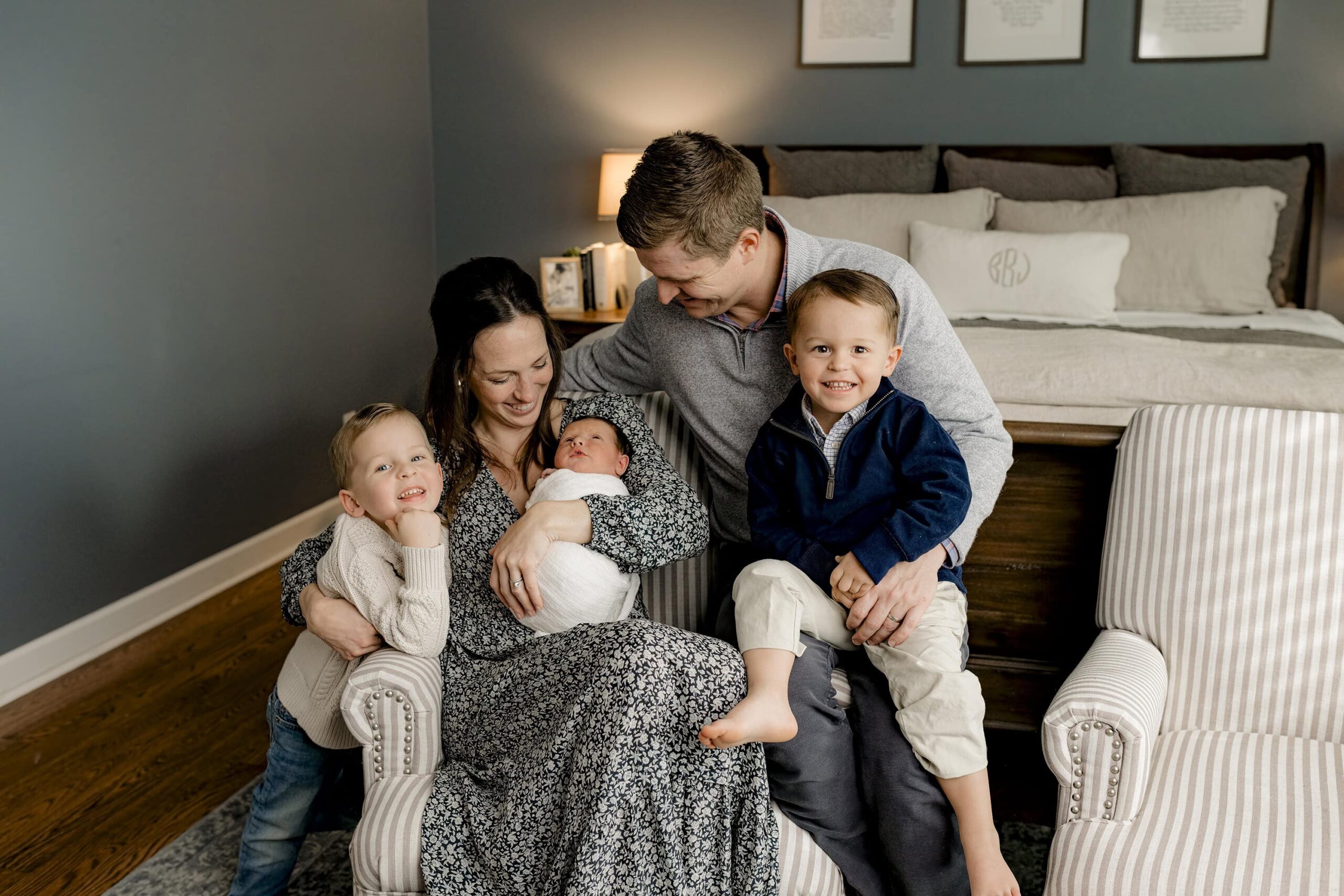 family of five in their lifestyle newborn session cuddling their newborn son in their classically styled room