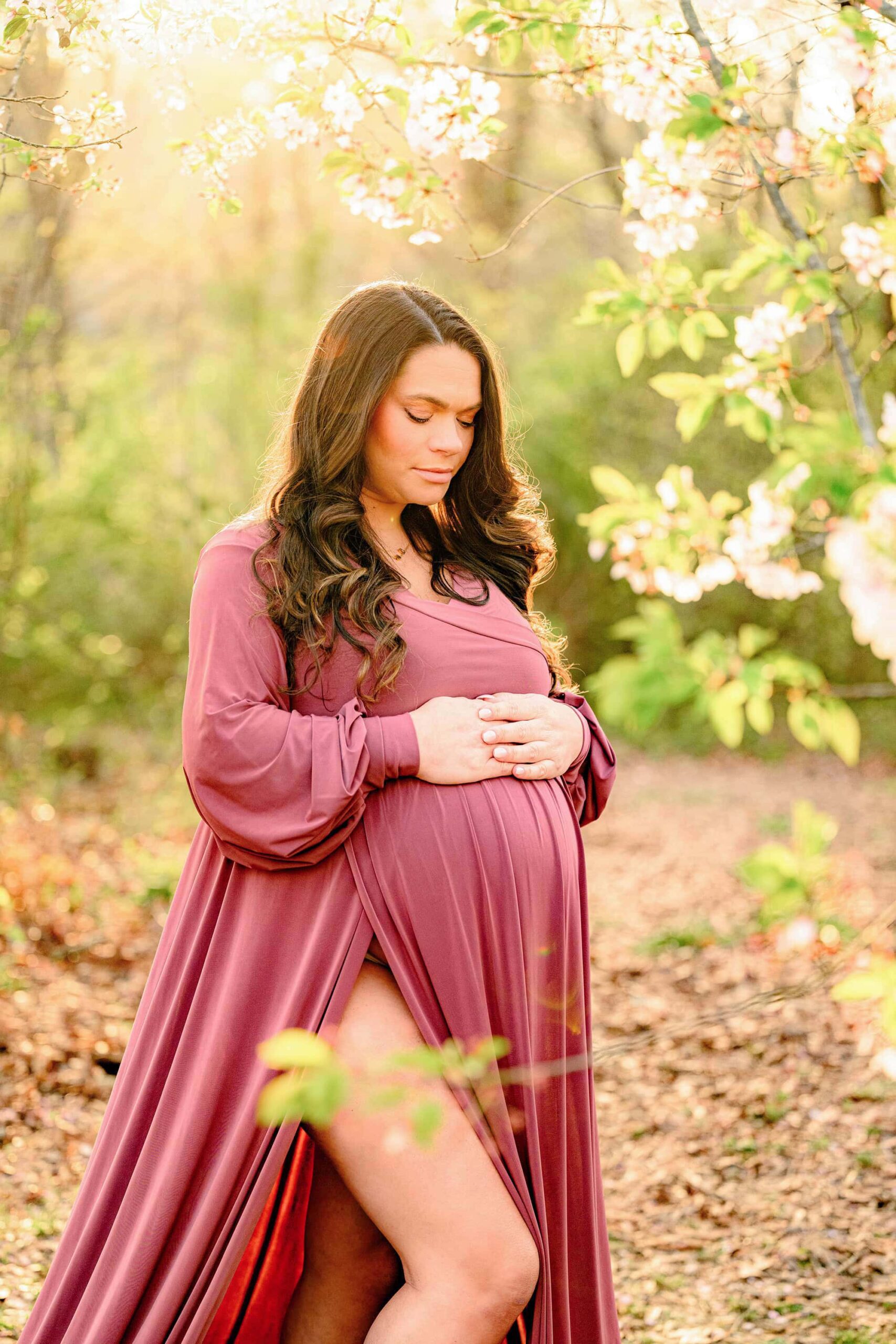 spring blooms surround this mom during her maternity session wearing a pink dress at a charlotte area location