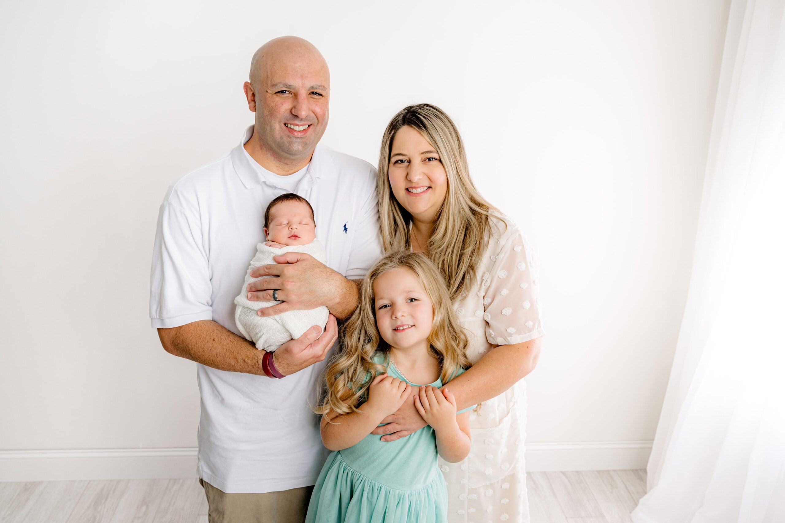 family of four all cuddled together in white and brown tones with pool blue accents