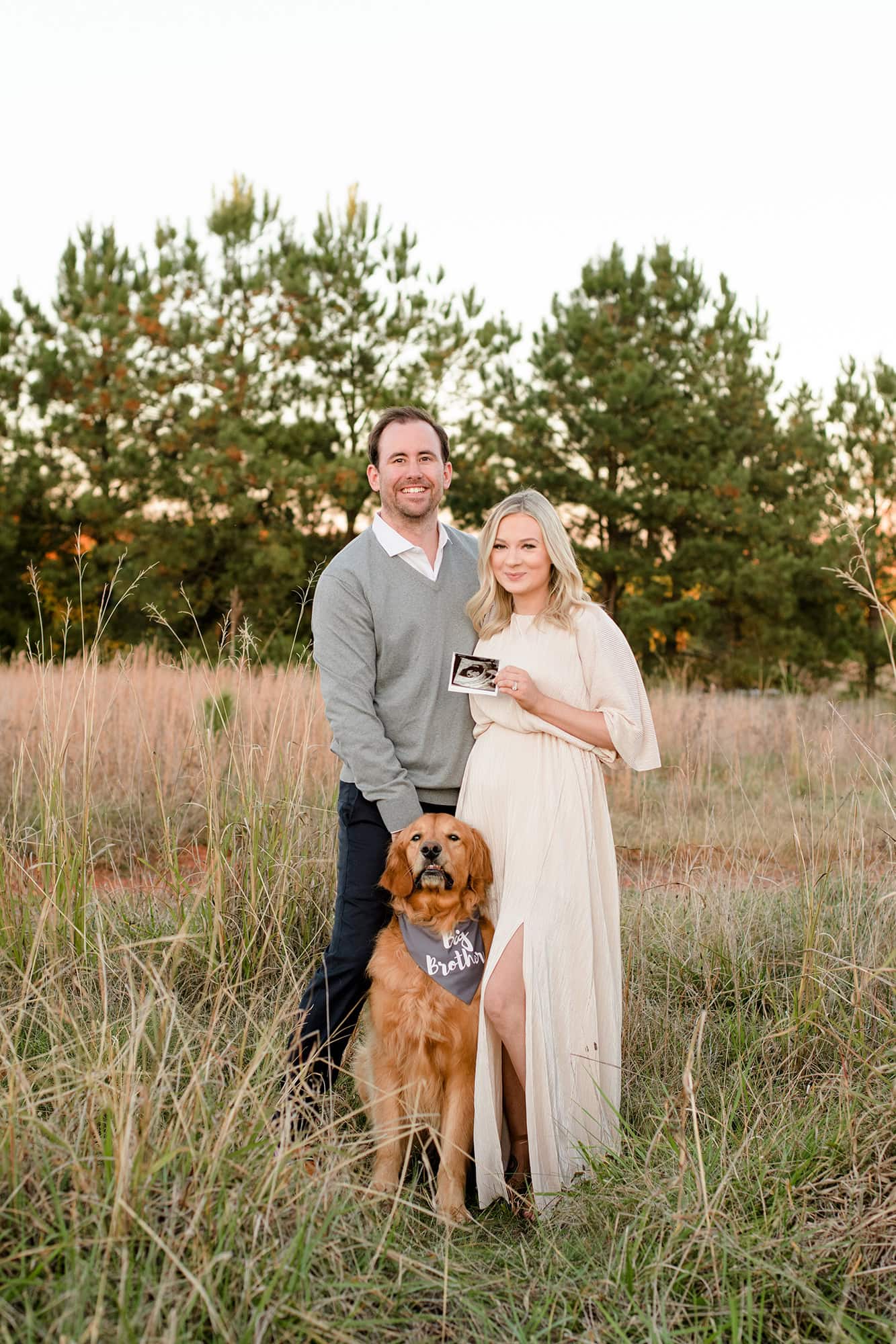 family photo of mom and dad expecting their first little girl with mom holding the ultrasound and dog wearing  big brother scarf