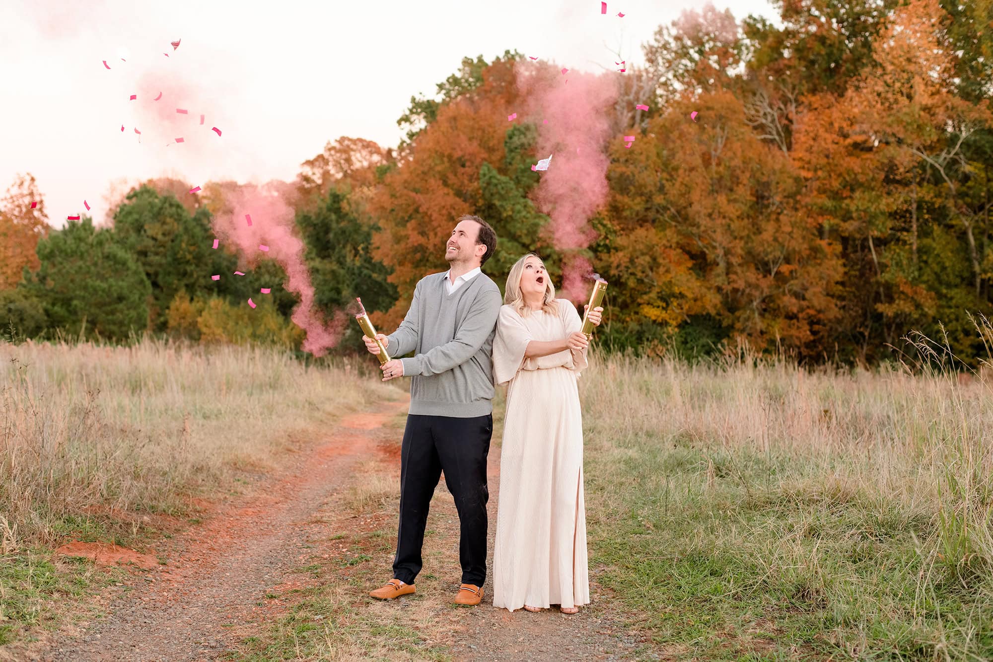 couples gender reveal session with confetti cannons in a tall field