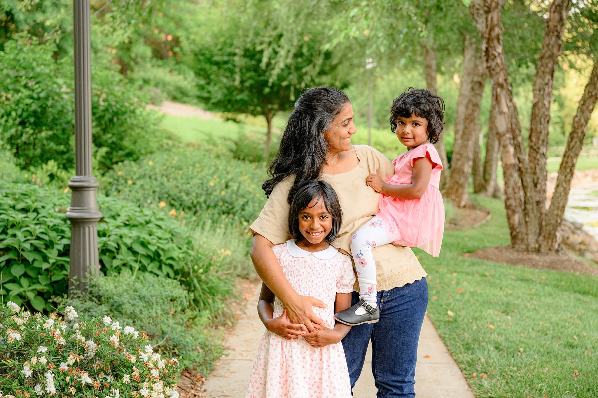mother holds her youngest daughter on her hip with her arm around her oldest having a fun family time together in charlotte nc