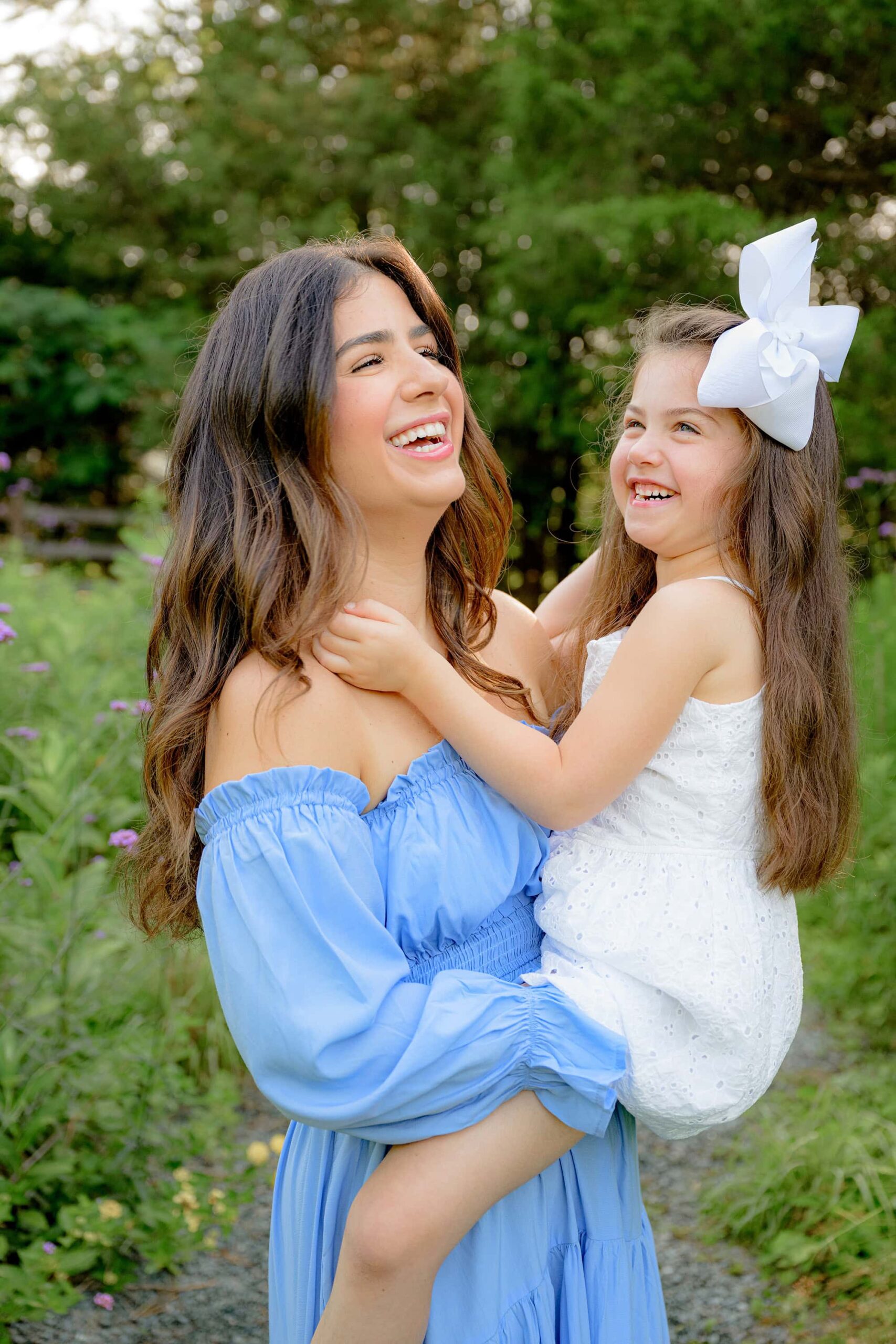 mom and daughter throwing their head backs laughing as they share a sweet moment while mom holds her daughter