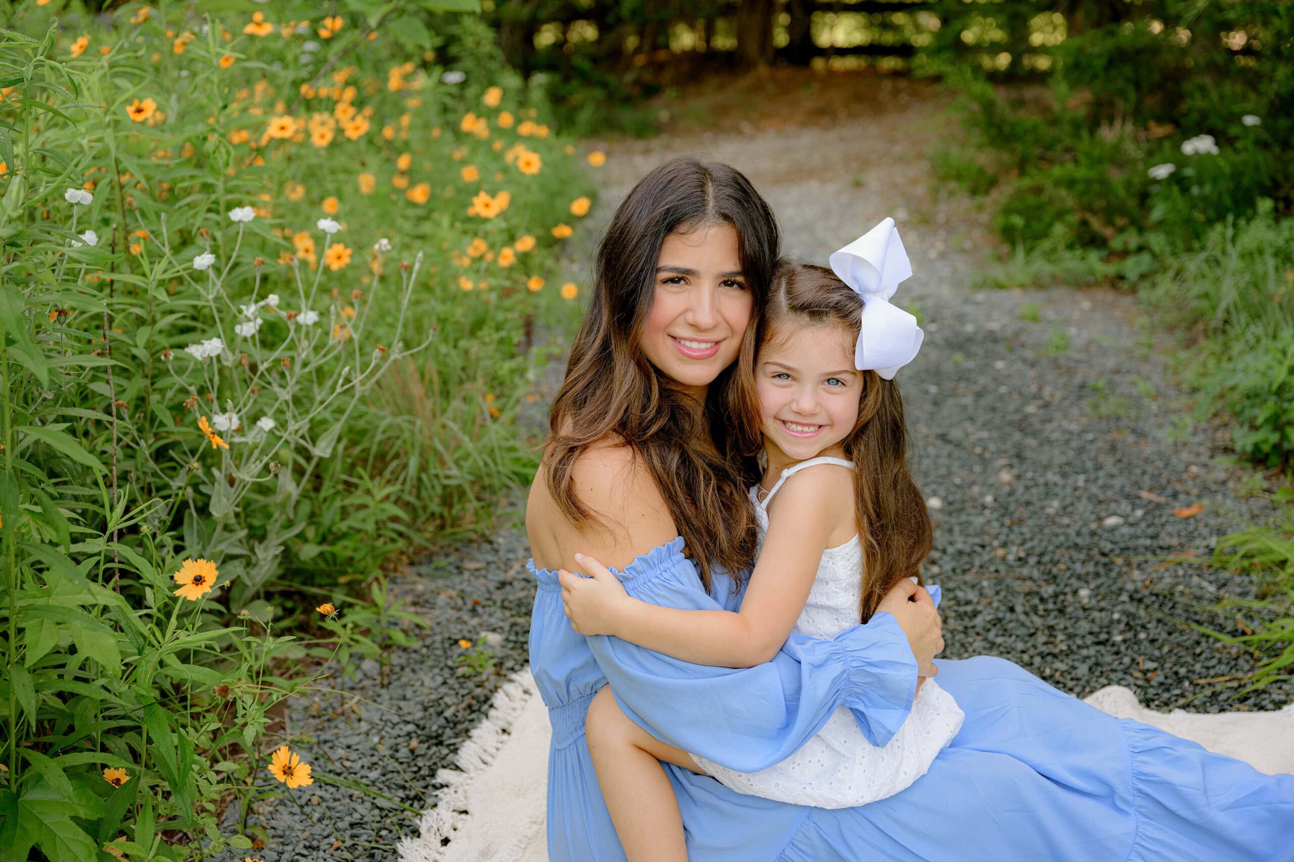 mother sits with daughter in her lap in a waxhaw area flower garden