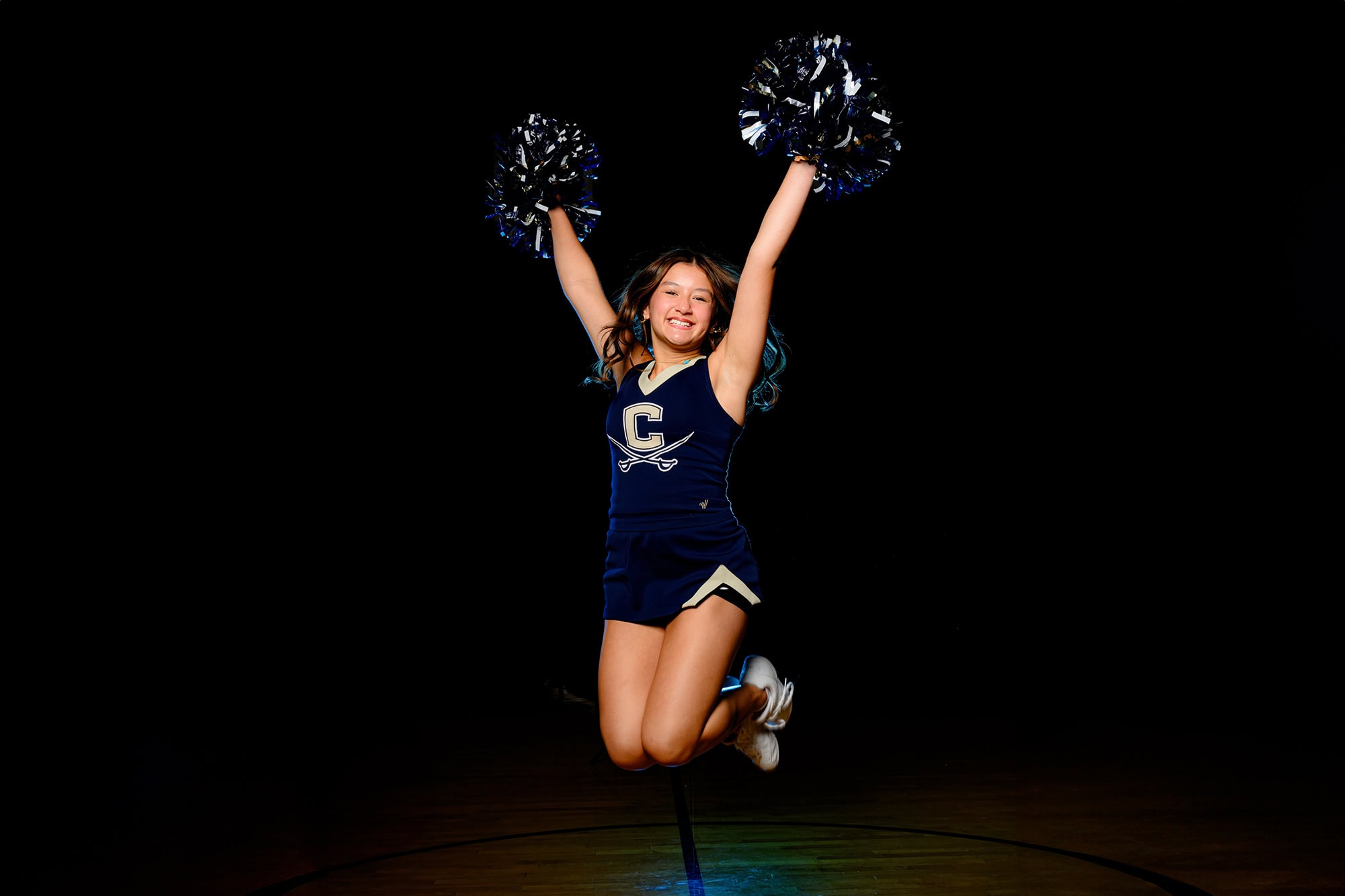 Cuthbertson High School cheerleader jumping with excitement with her arms and poms in the air during their media day session