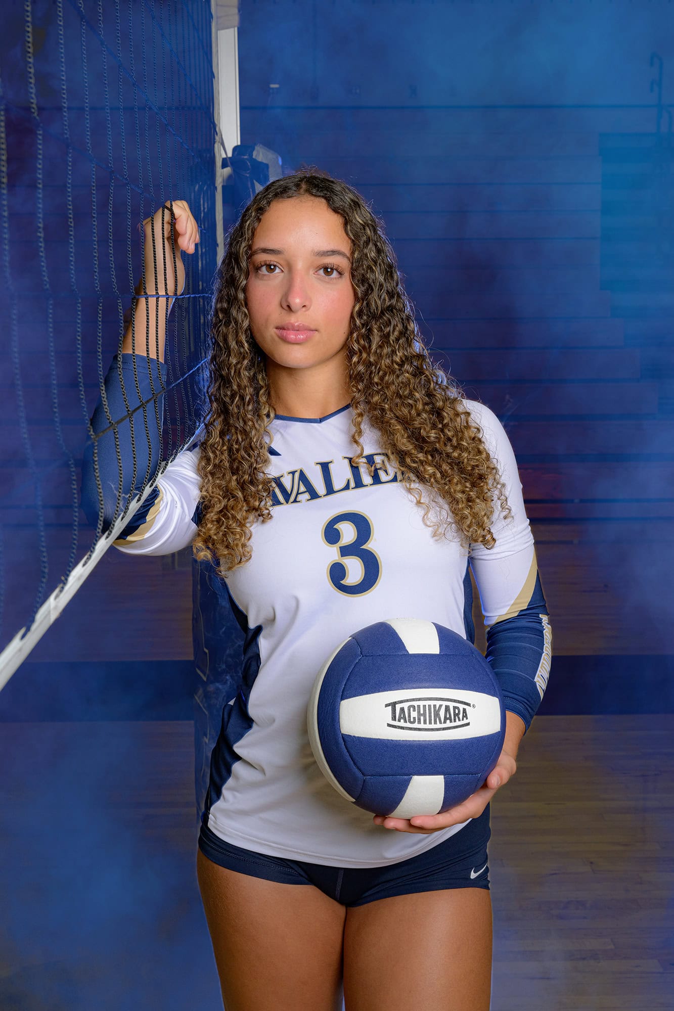 number 3 on cuthbertson varsity volleyball standing beside a net holding a ball during media day