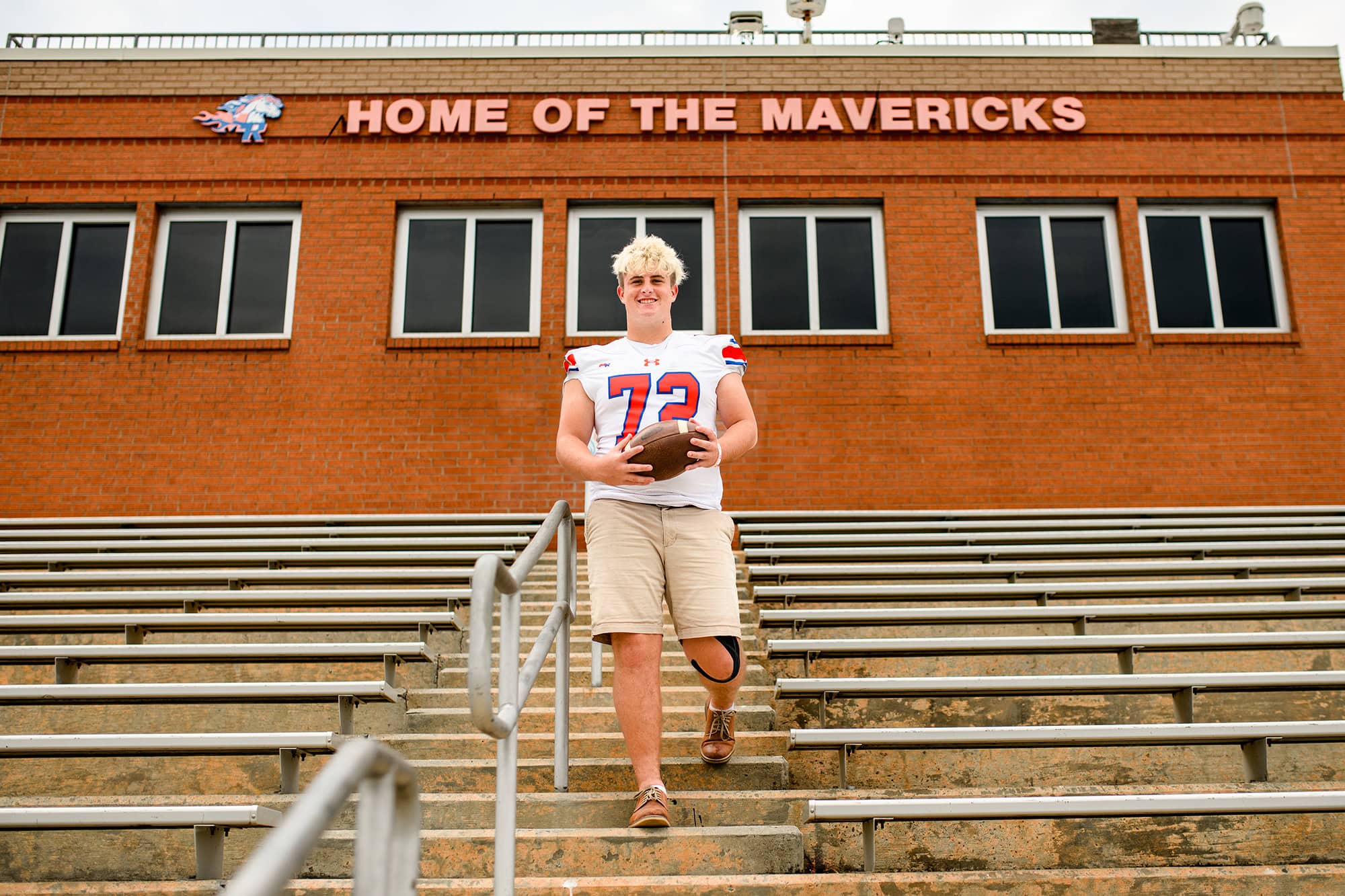 High school senior night photo used for charlotte area graduate of marvin ridge wearing his jersey, holding a football, and standing in his home stadium