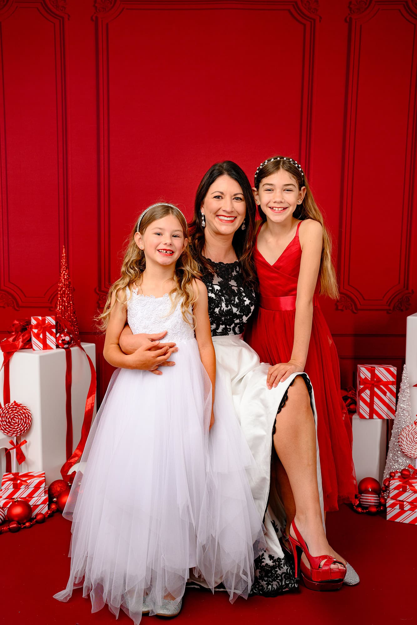 mother hugging her two daughters in a Charlotte christmas set up