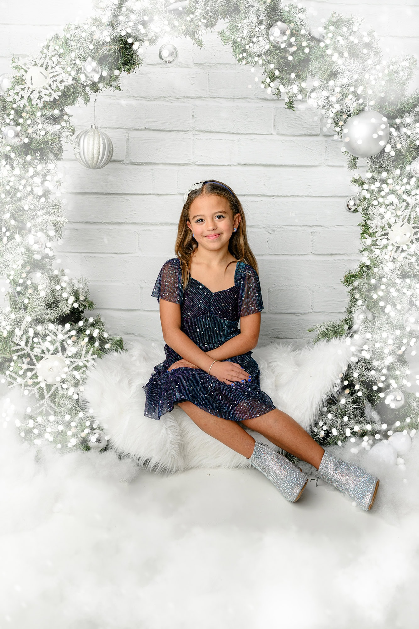 little girl sitting in a charlotte holiday set up dresses in blue with silver boots