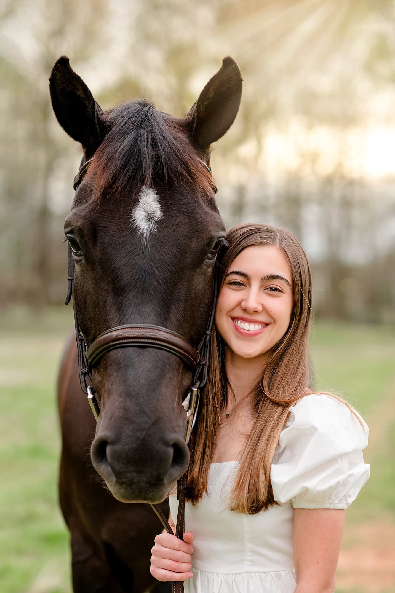 dark hair charlotte graduate stands in white dress with her horse beside her
