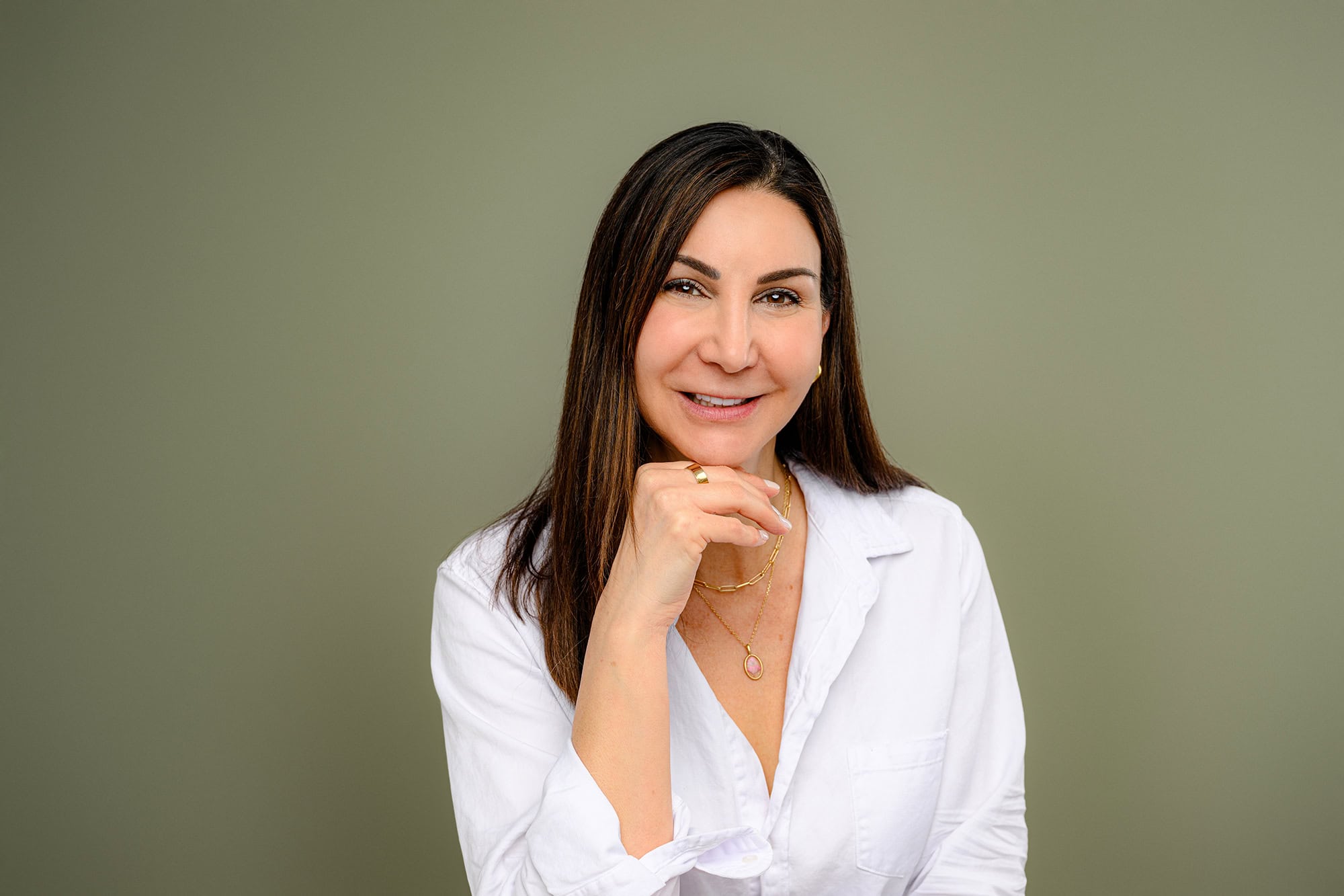 casually styled studio headshot of client wearing a white shirt on a green background