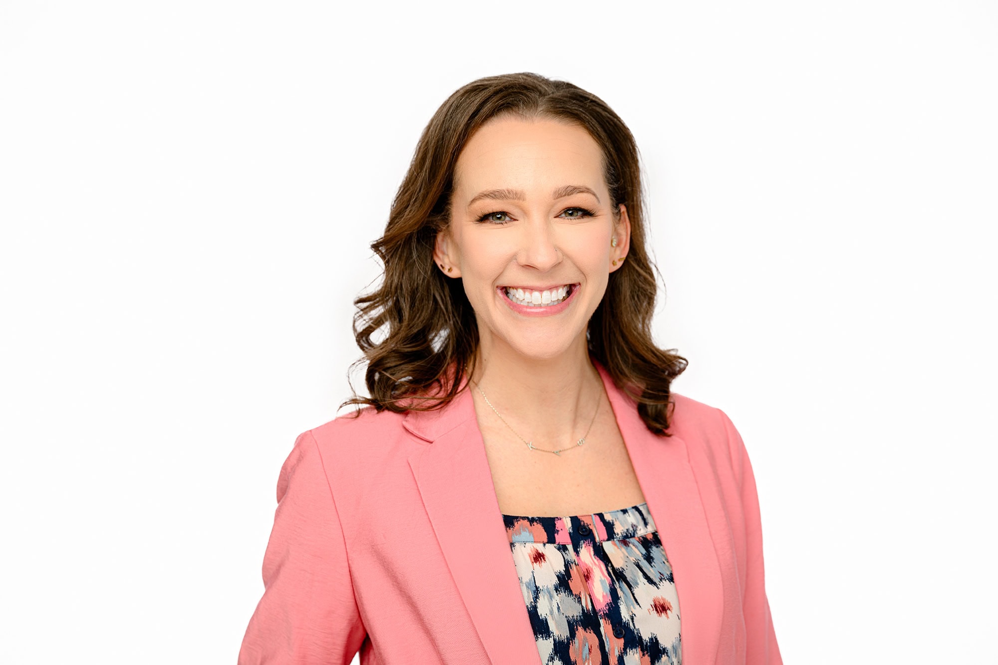 dark hair client wearing peach jacket and shirt for her studio headshots styled on a white background