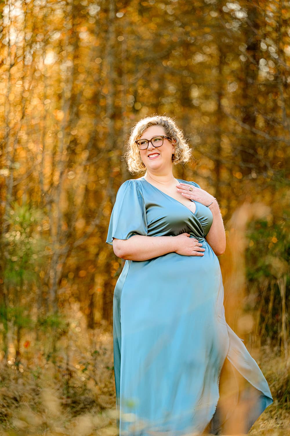 blonde pregnant mother to be laughs during her maternity photos wearing a blue wrap dress