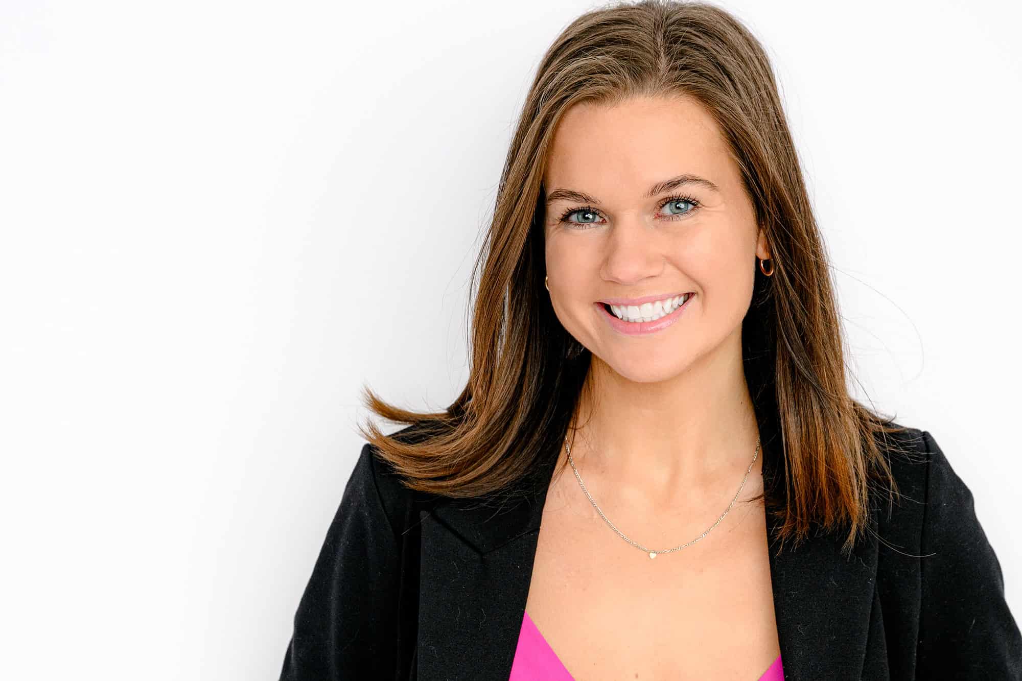 Corporate headshot of woman with dark brown hair wearing a pink top and black blazer