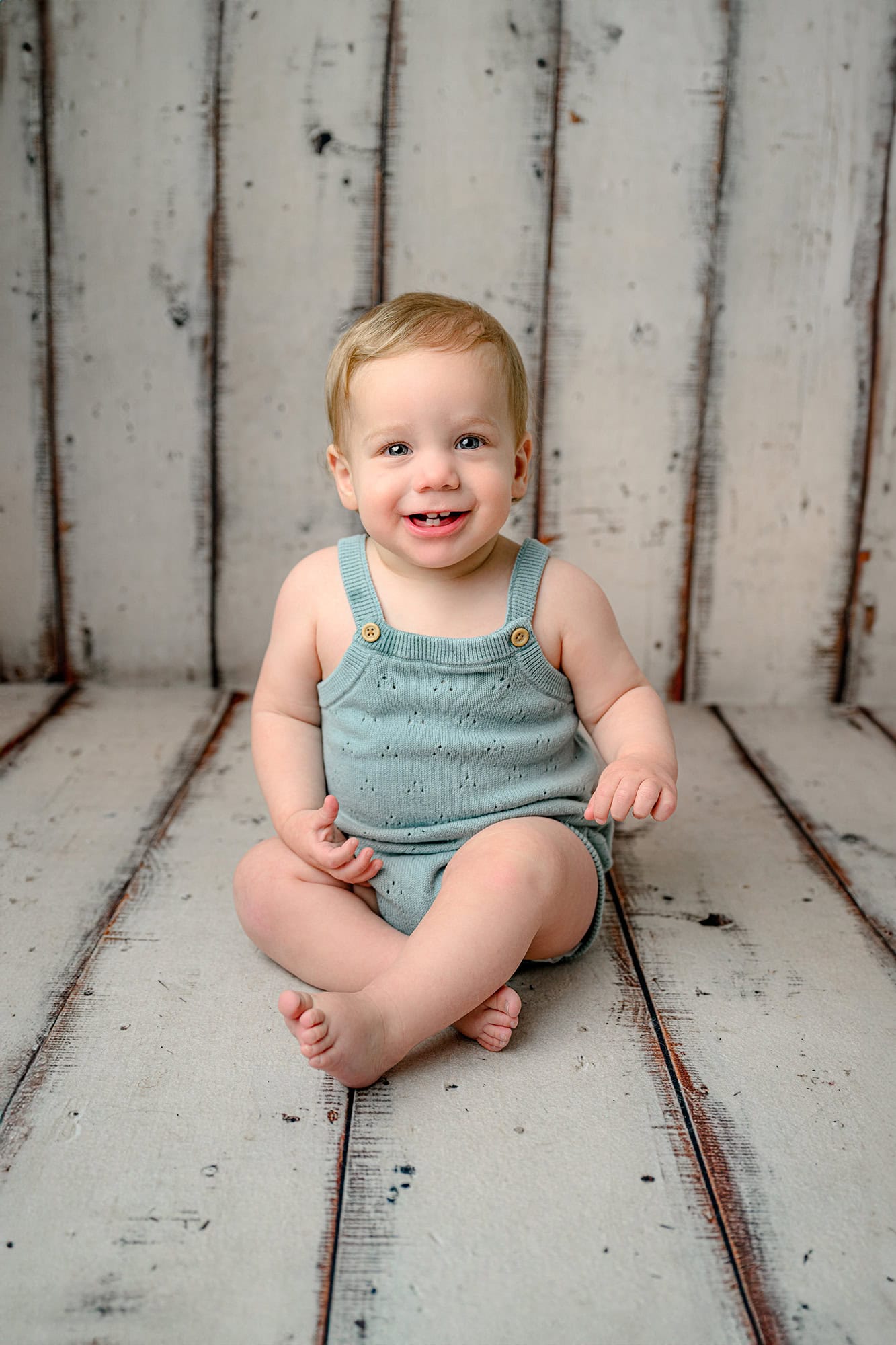 milestone photo of one year old charlotte boy sitting and wearing a blue romper