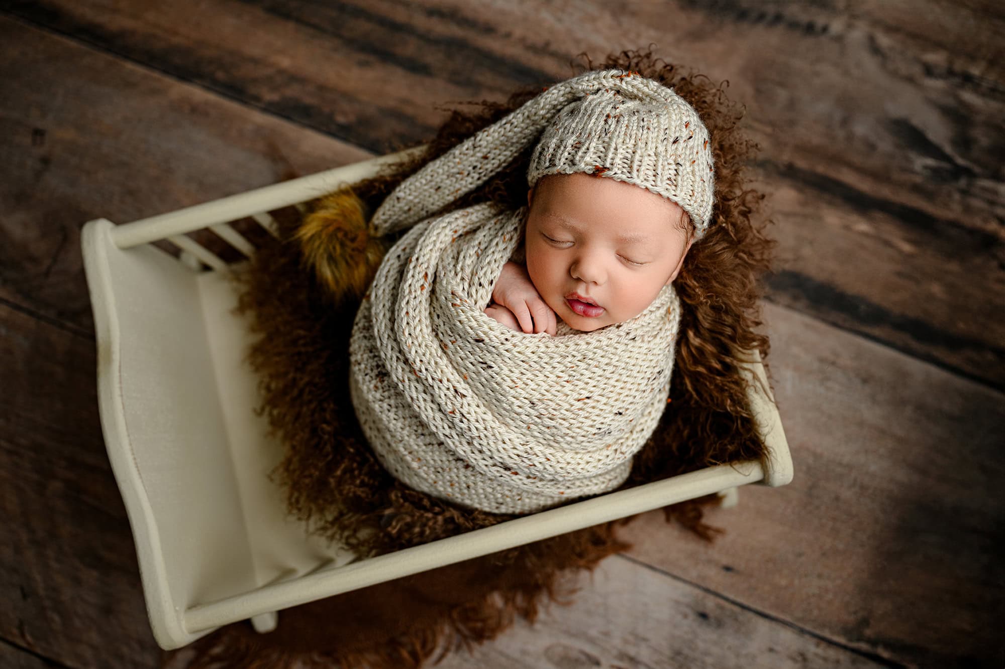 newborn photo of baby wearing a sleepy cap wrapped during his studio portraits 